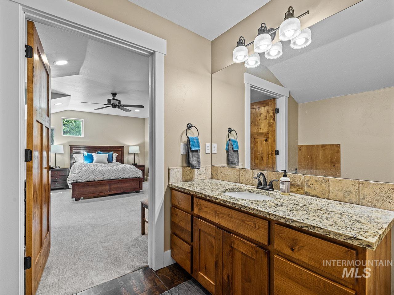 Ensuite bathroom with vanity, lofted ceiling, a ceiling fan, and wood finished floors