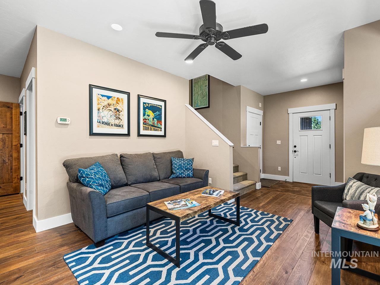 Living area featuring stairs, wood-type flooring, a ceiling fan, and recessed lighting