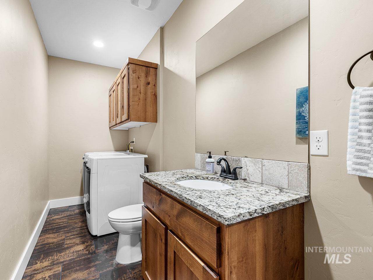 Half bathroom with washer / clothes dryer, wood finished floors, and vanity