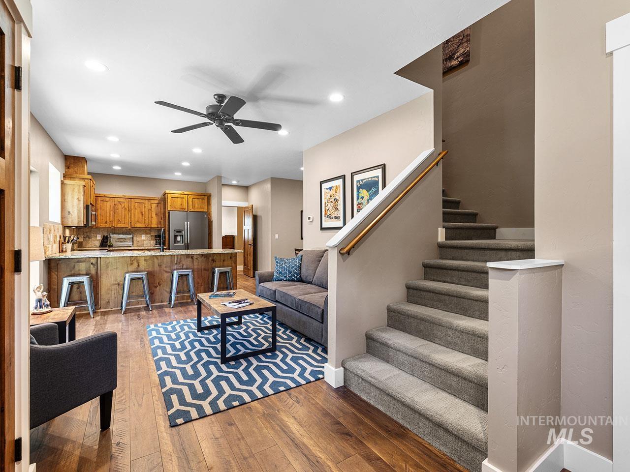Living area featuring ceiling fan, wood-type flooring, recessed lighting, and stairway