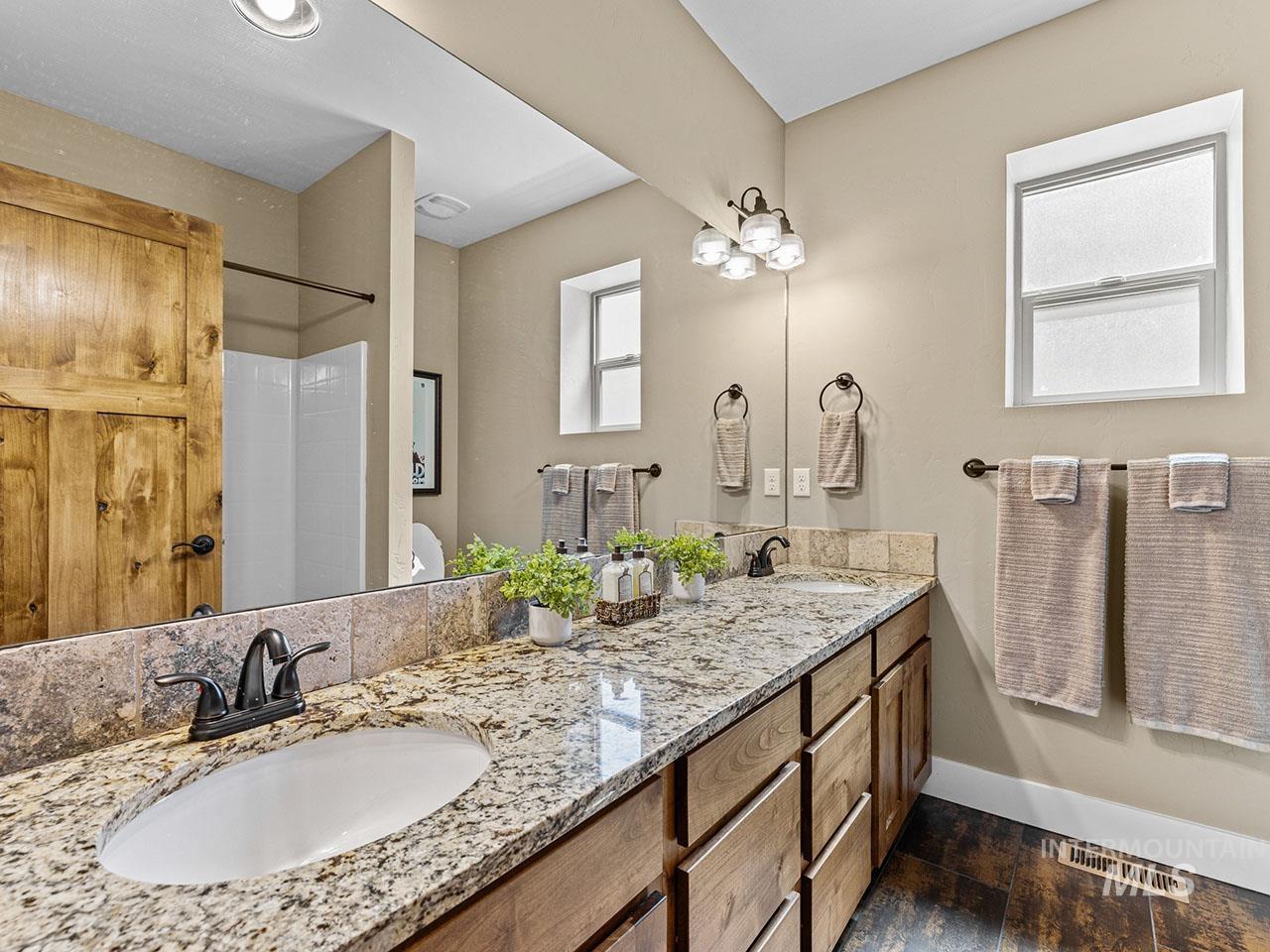 Bathroom with double vanity, wood finished floors, healthy amount of natural light, and a shower