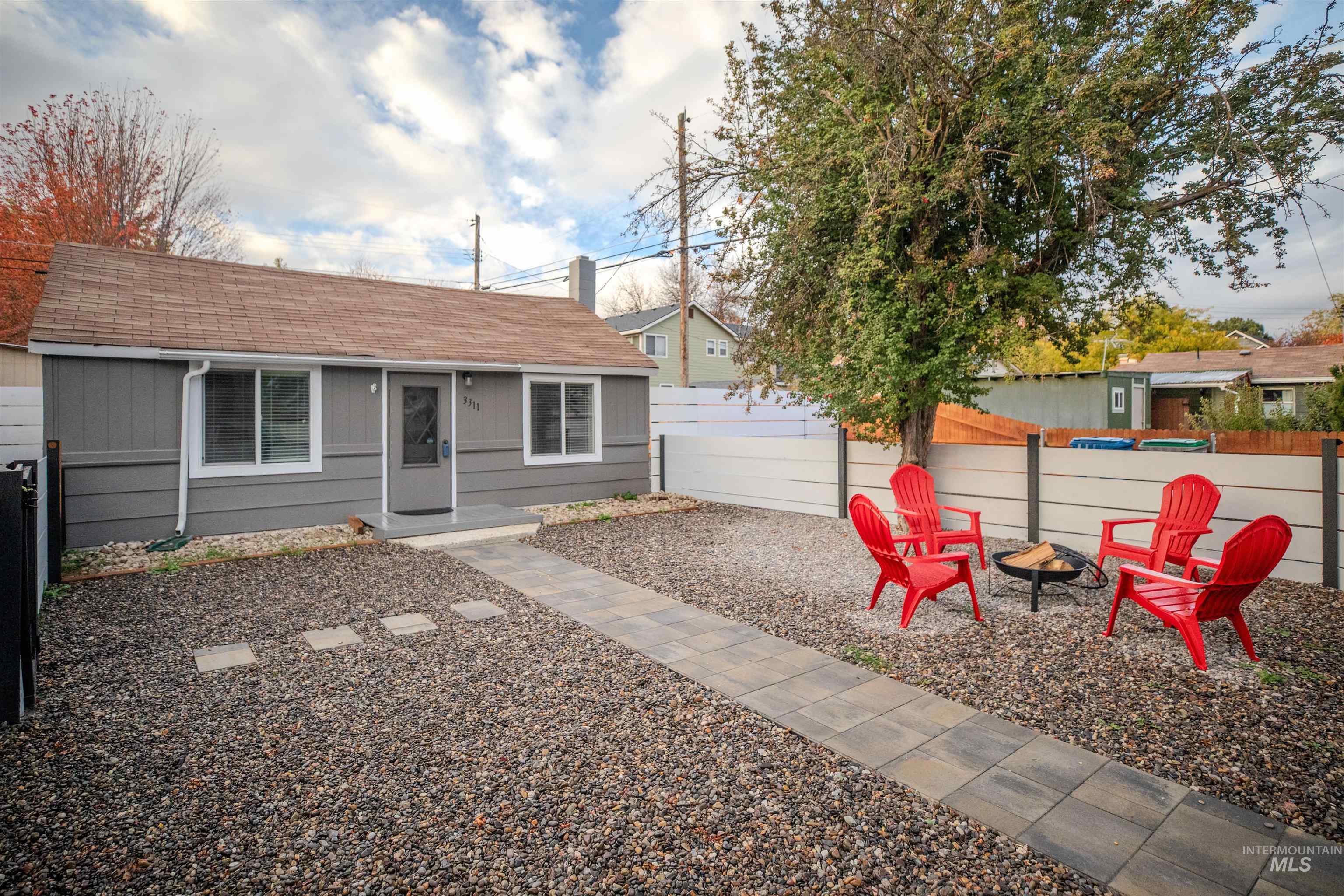 View of front of property with a fire pit, roof with shingles, and a fenced yard
