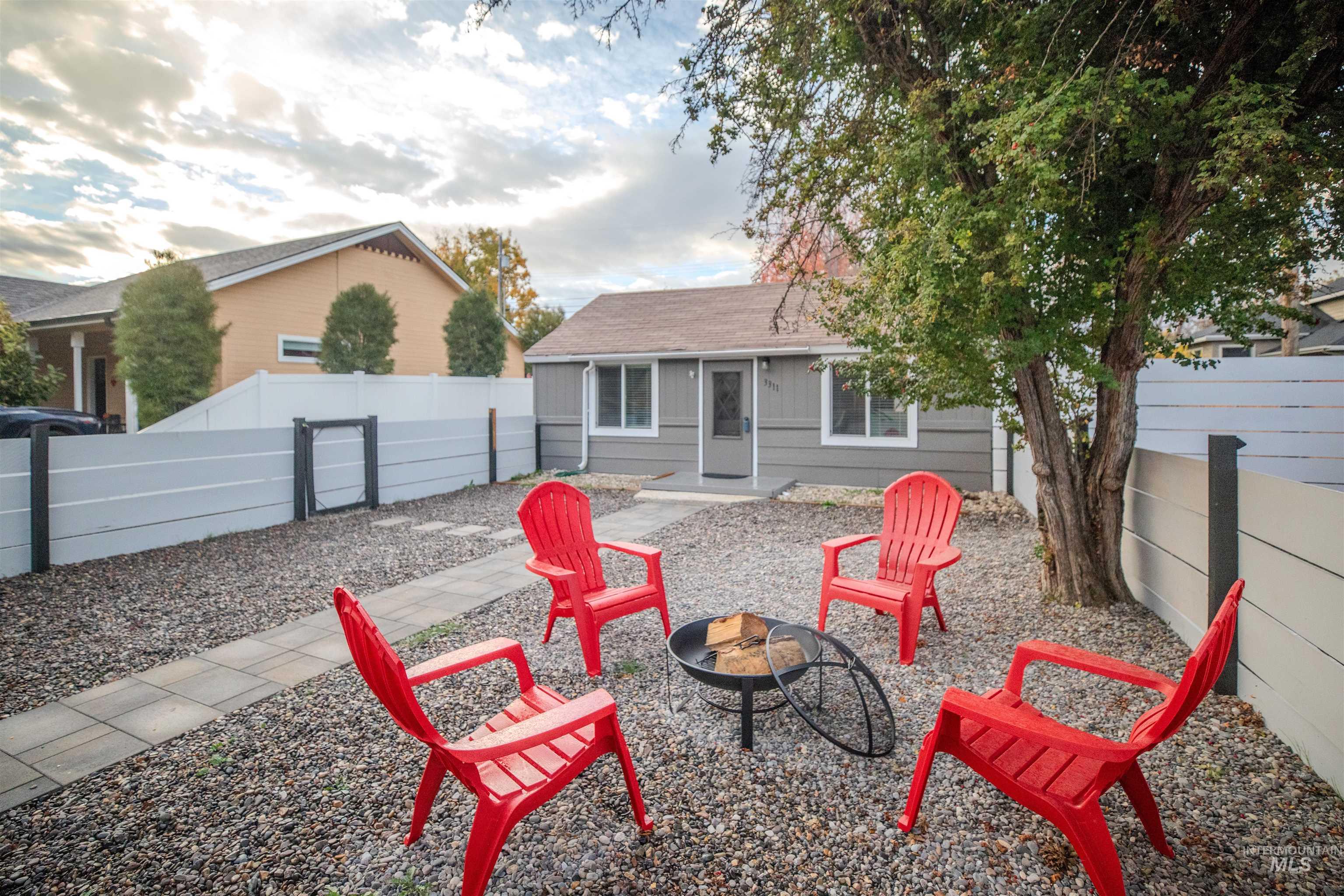 Front view of house with a fenced yard, a fire pit, and a shingled roof