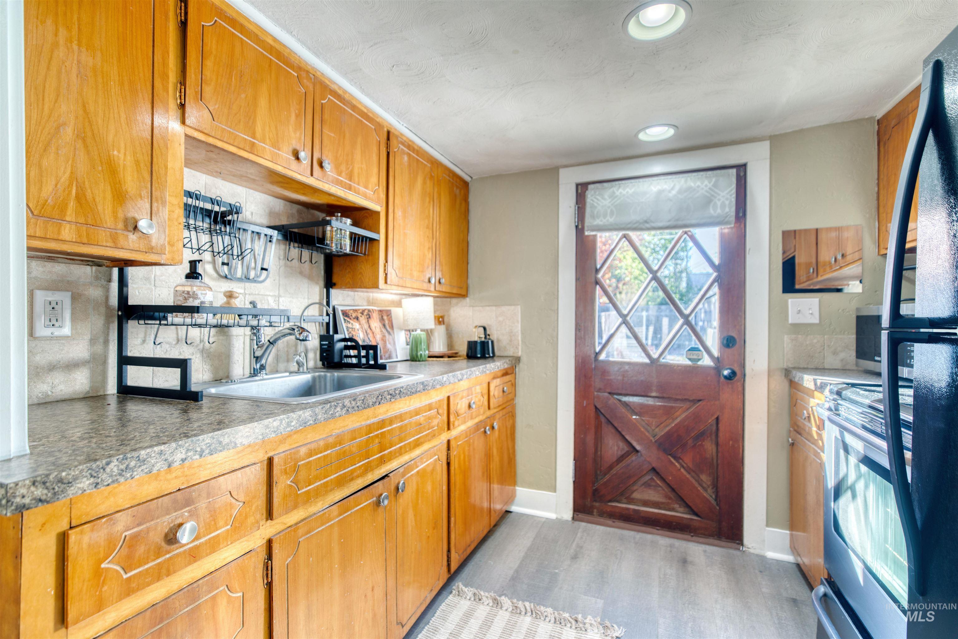 Kitchen featuring stainless steel range oven, backsplash, light wood finished floors, and brown cabinets