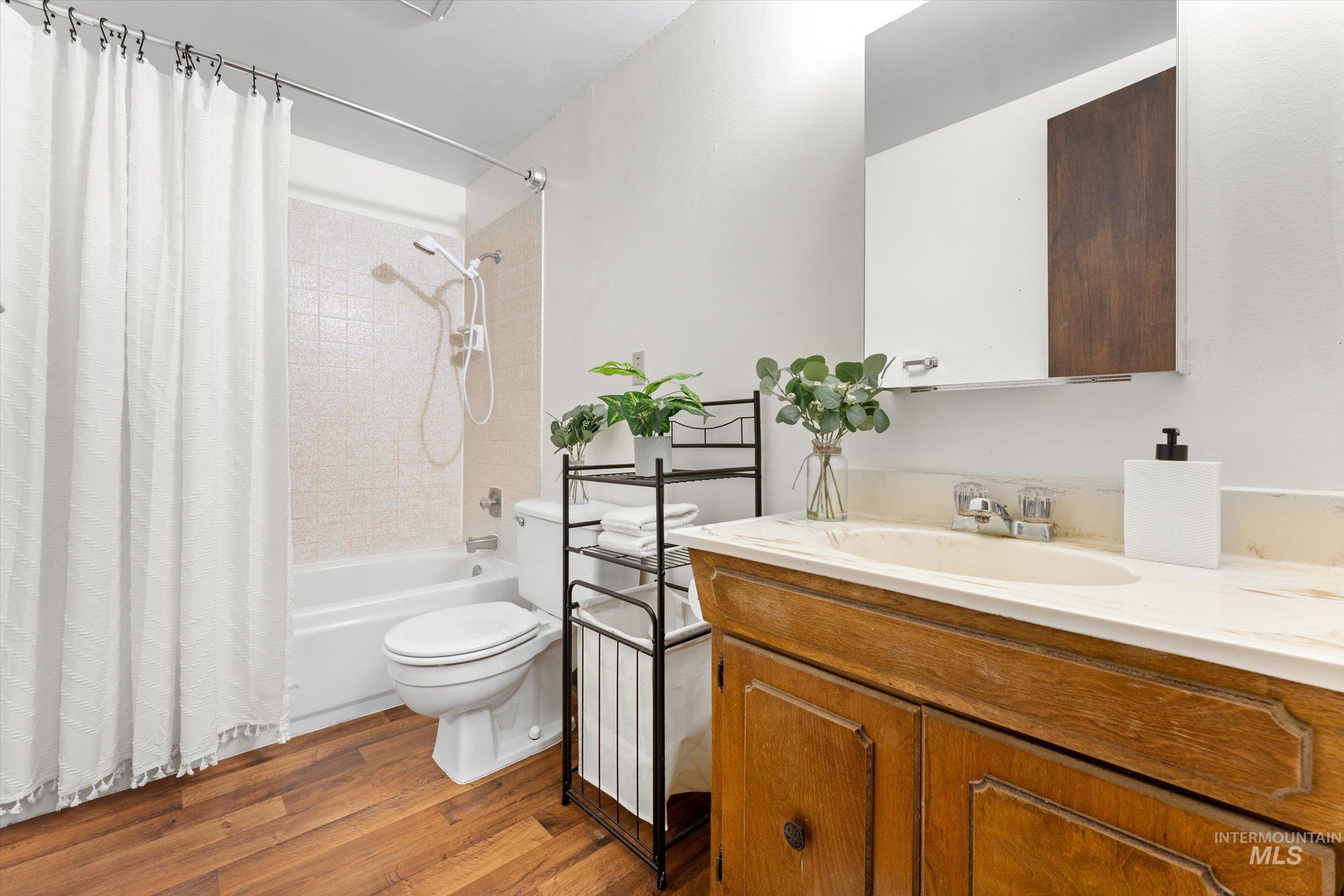 Full bath featuring vanity, light wood-style flooring, and shower / bathtub combination with curtain