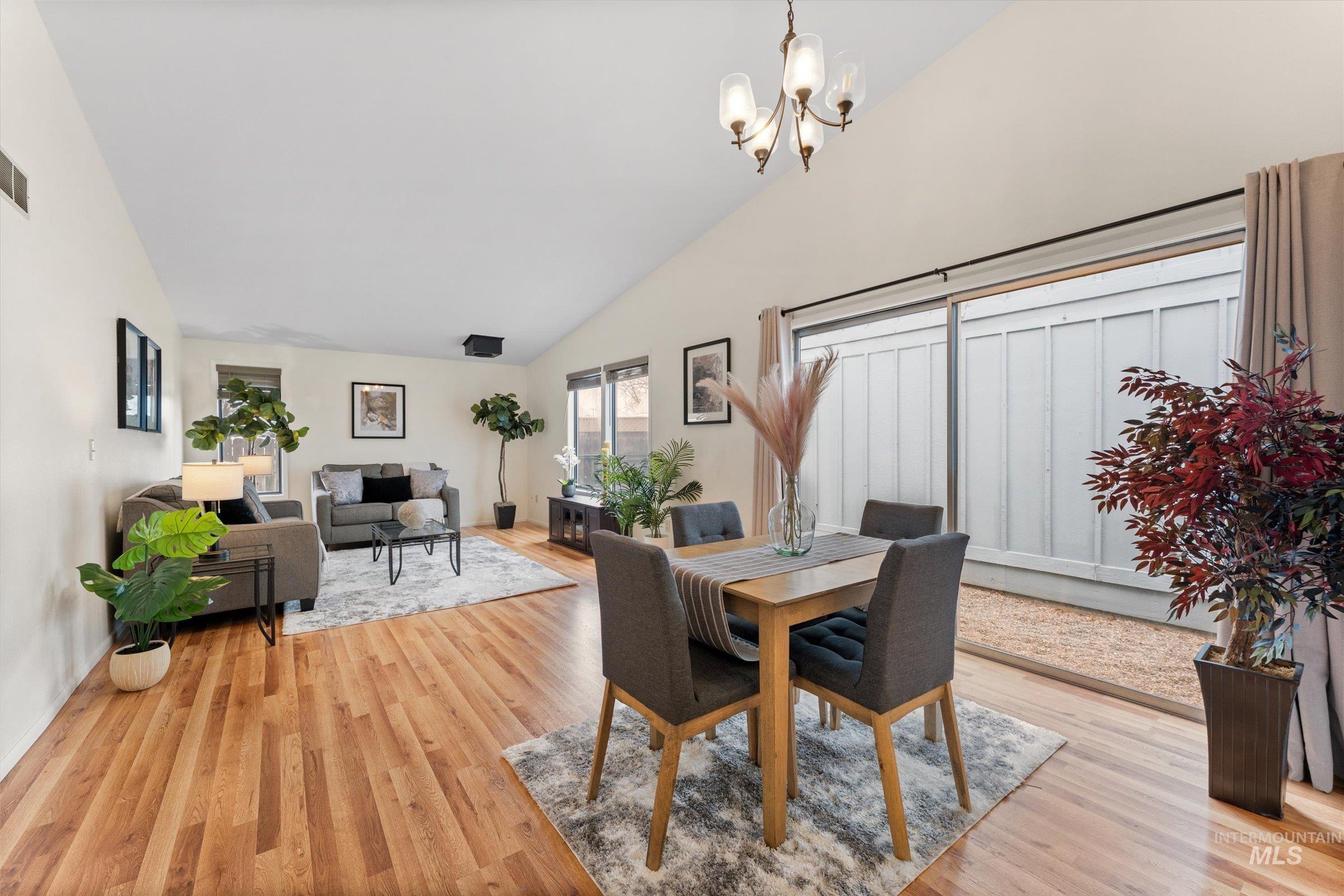 Dining area with vaulted ceiling, light wood-style flooring, and hanging lights