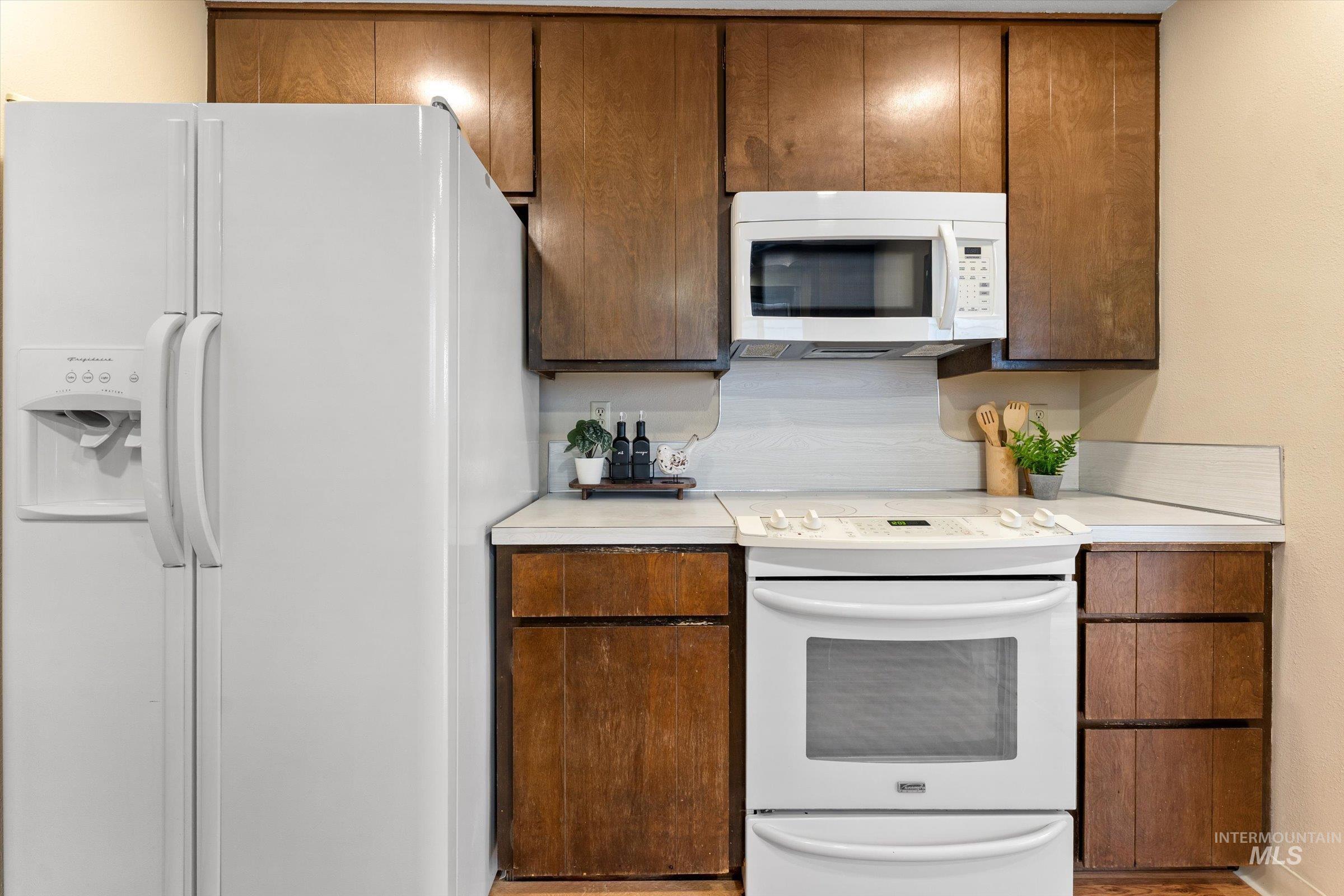 Kitchen with white appliances, light countertops, and wood finish cabinetry