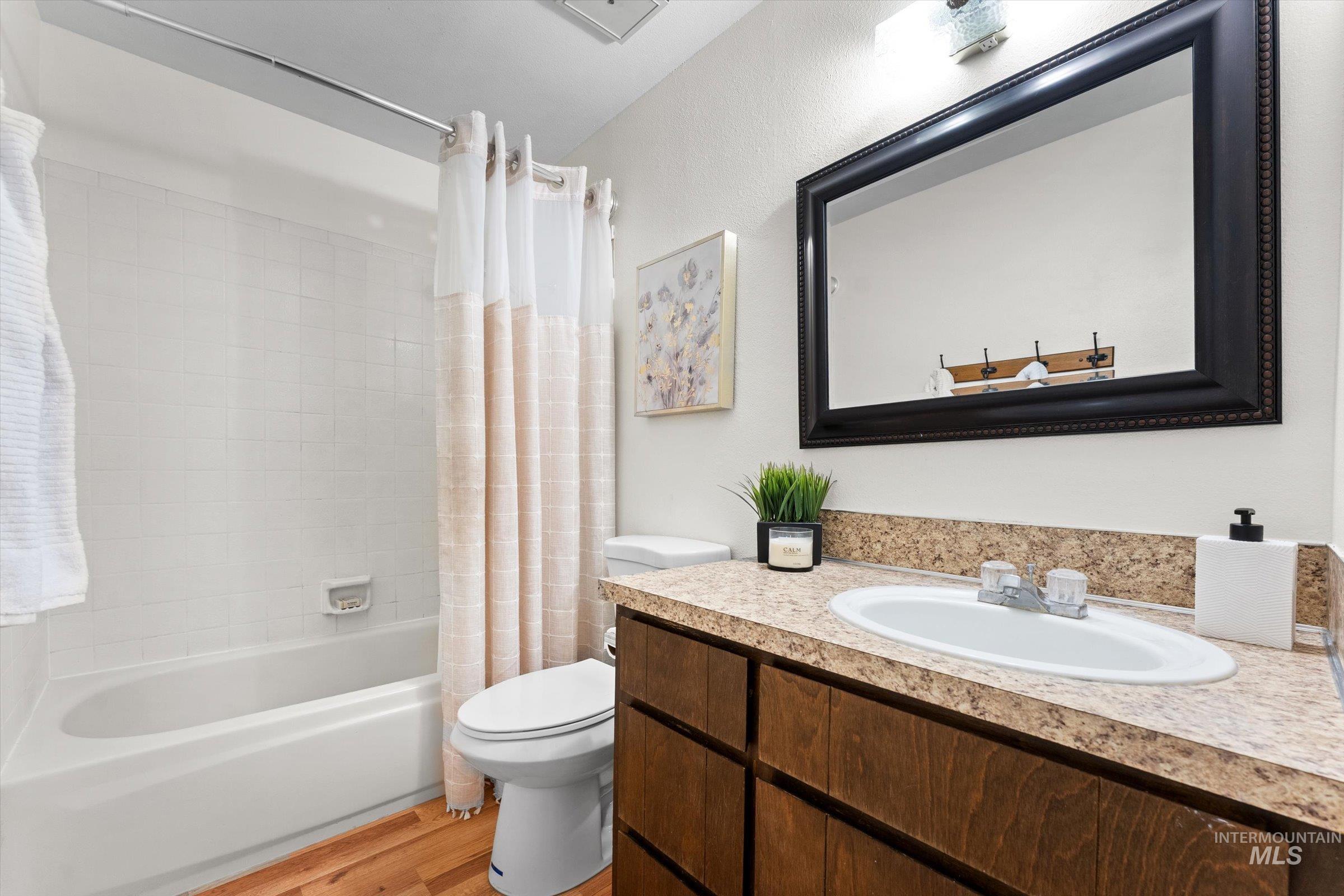 Bathroom featuring vanity, shower / bath combo, and light wood-style floors