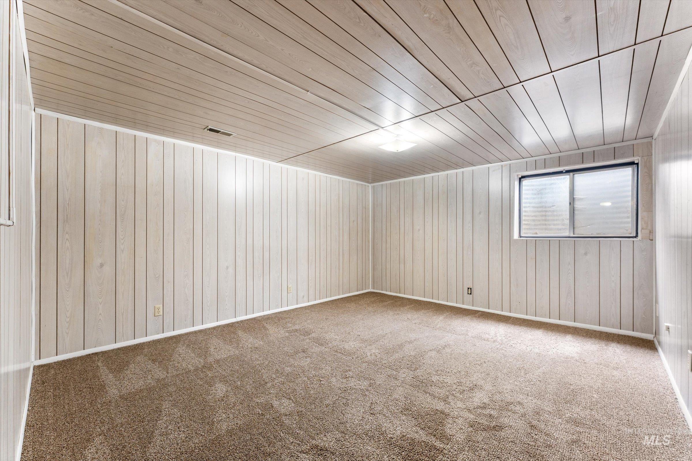Spare room with wood walls, wooden ceiling, and carpet floors