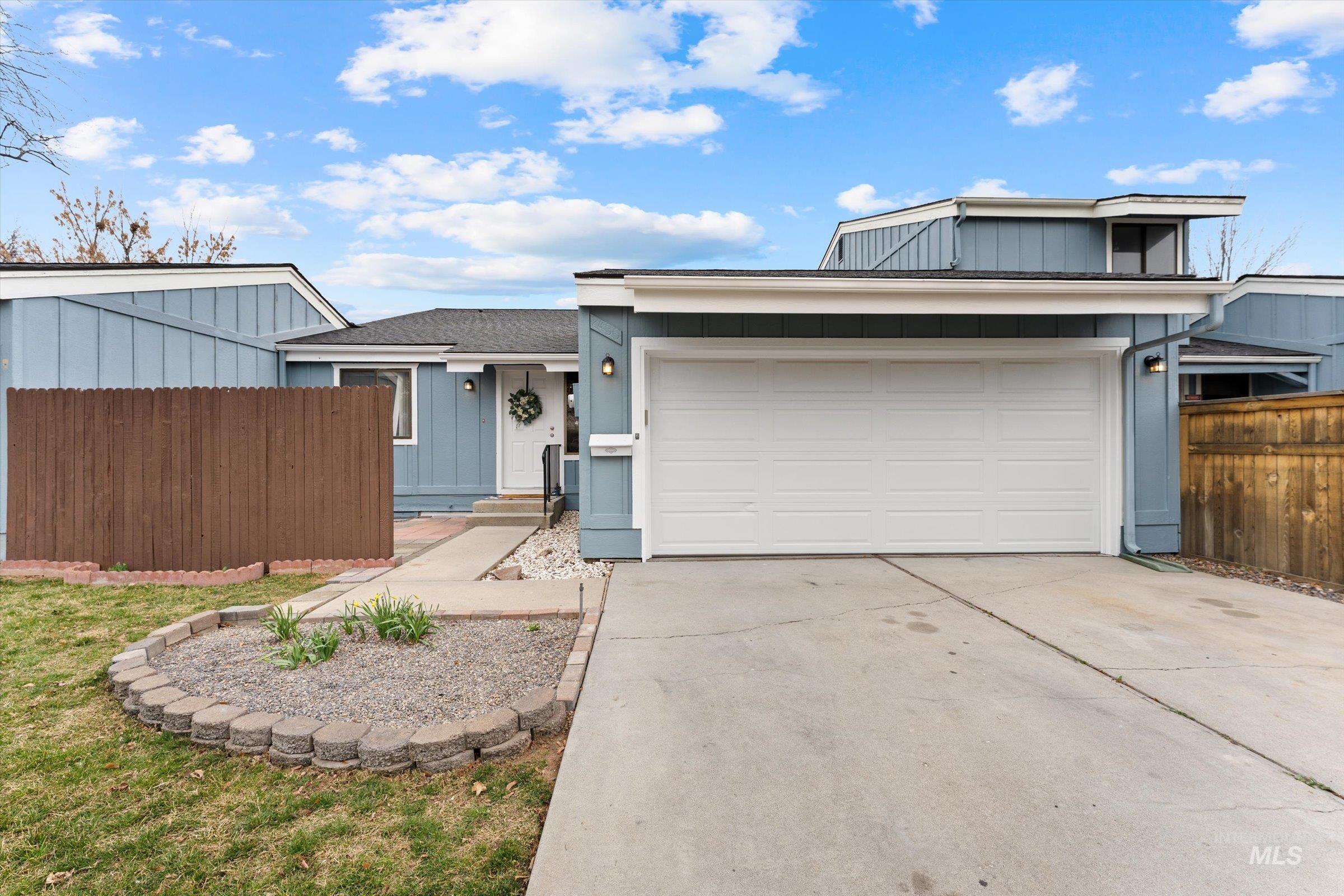 View of front facade with board and batten siding, driveway, a garage, and roof with shingles