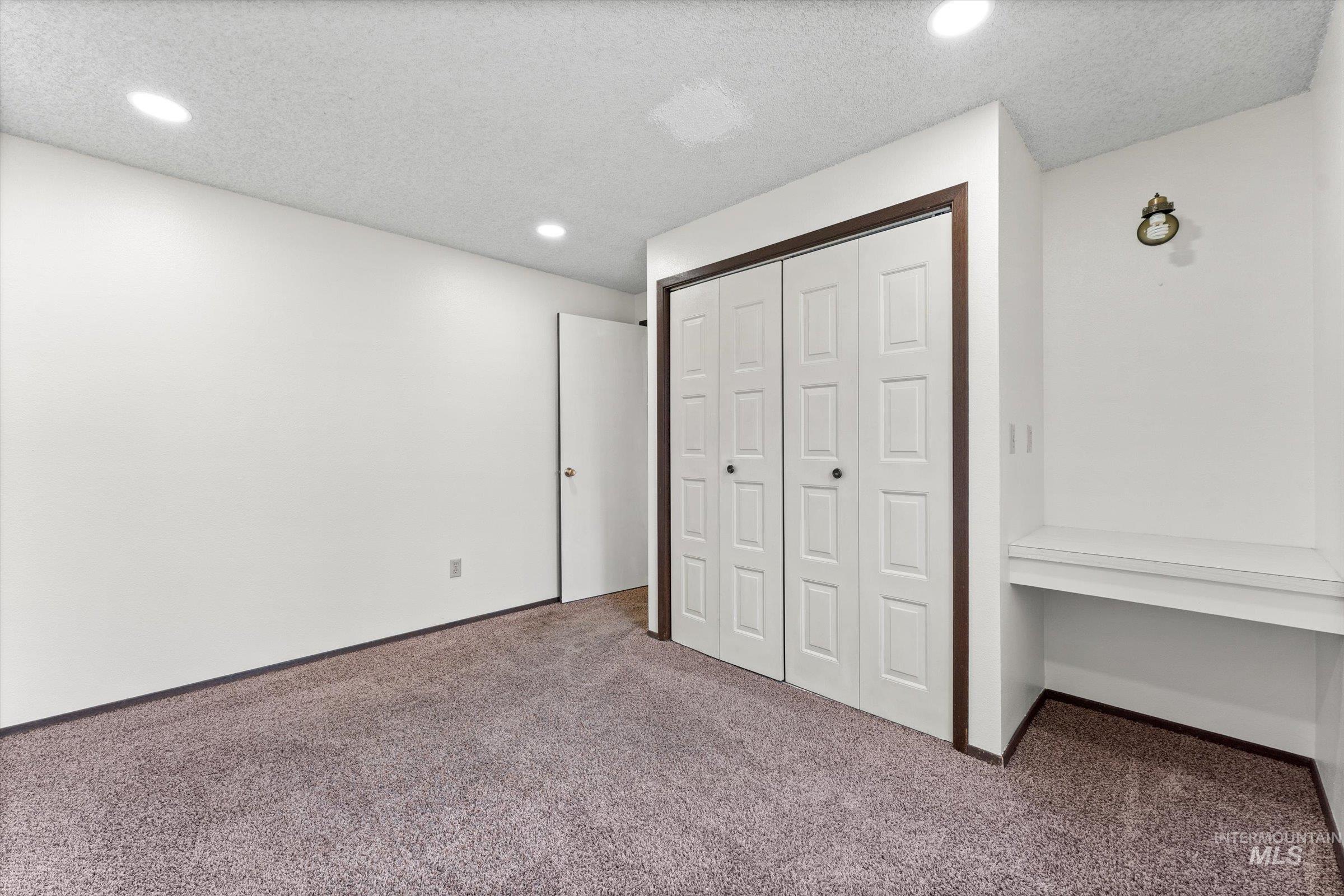 Unfurnished bedroom featuring carpet floors, a closet, a textured ceiling, and recessed lighting