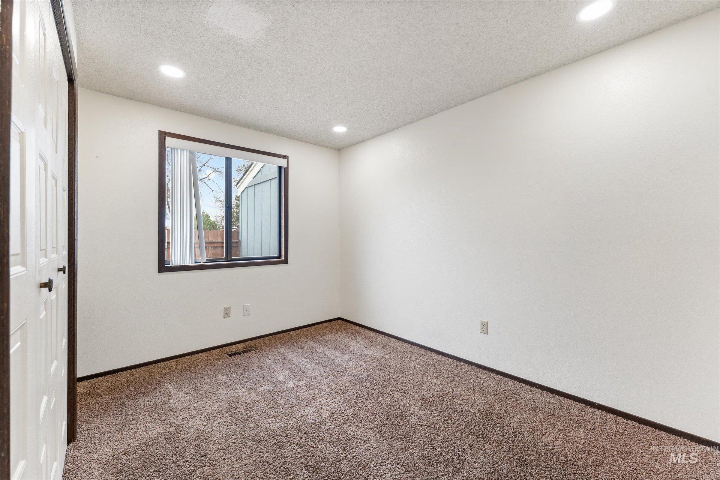 Spare room featuring carpet flooring, a textured ceiling, and recessed lighting