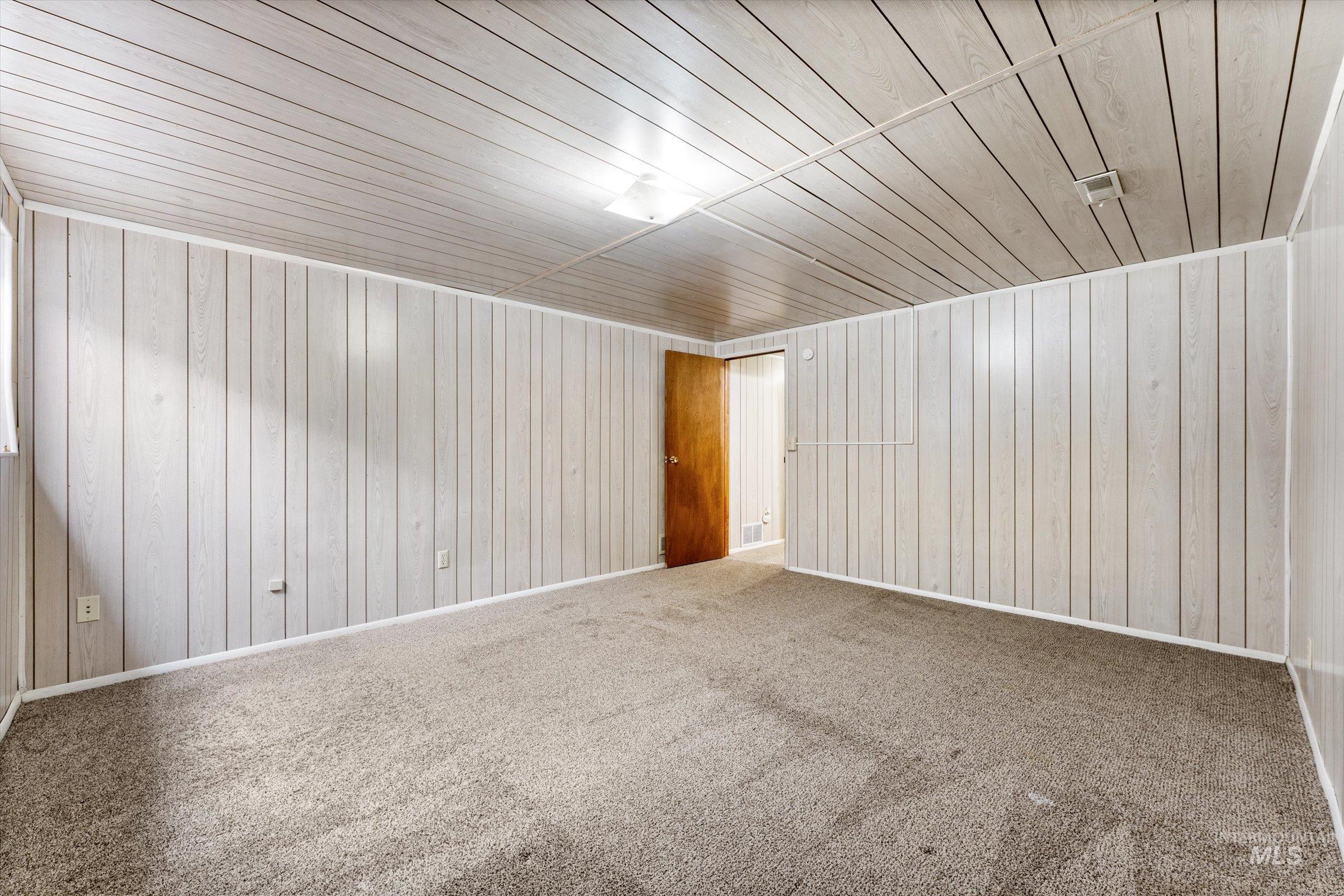 Carpeted empty room with wooden ceiling and wooden walls