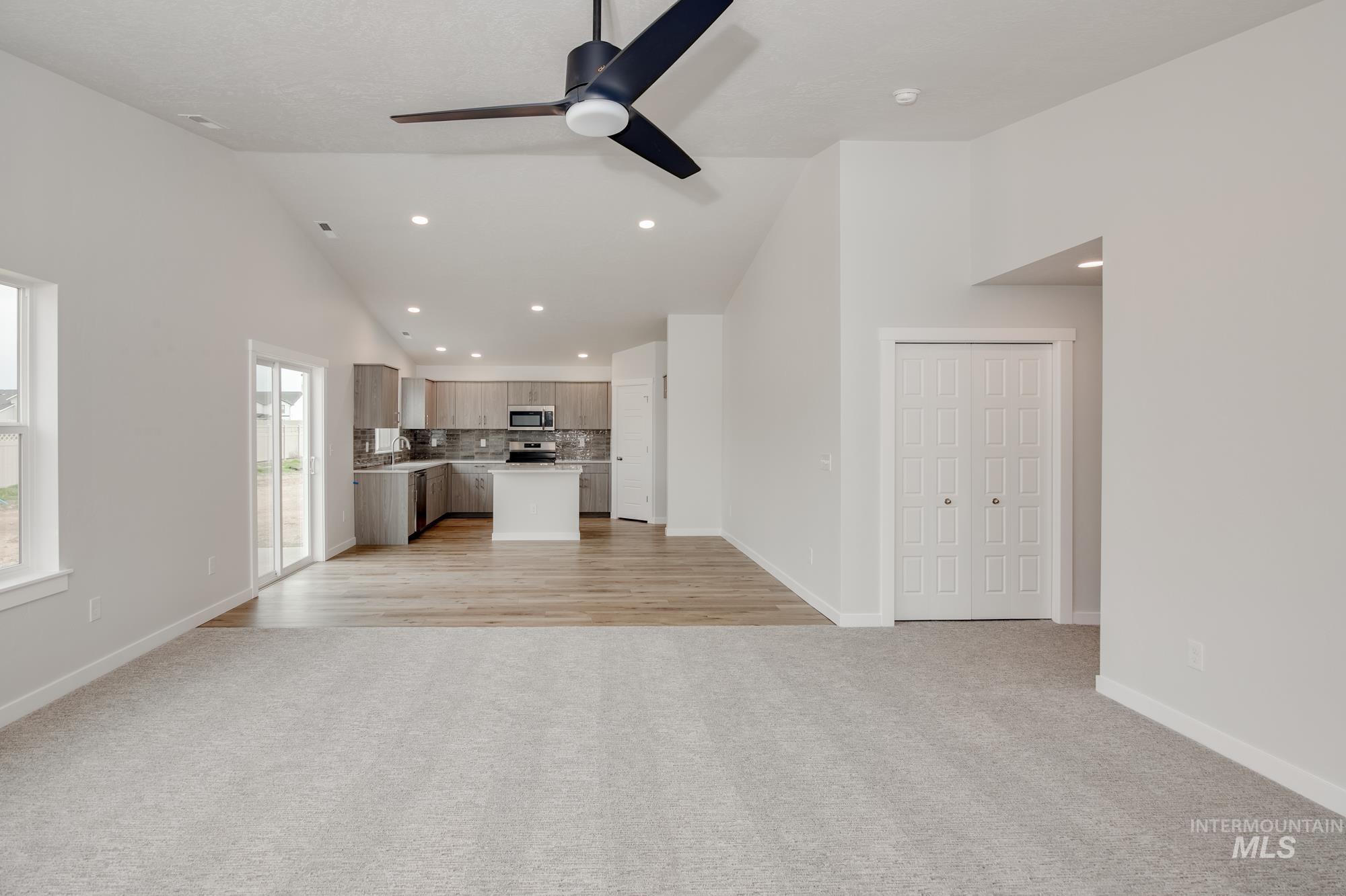 Open-concept living space featuring vaulted ceilings and a modern ceiling fan