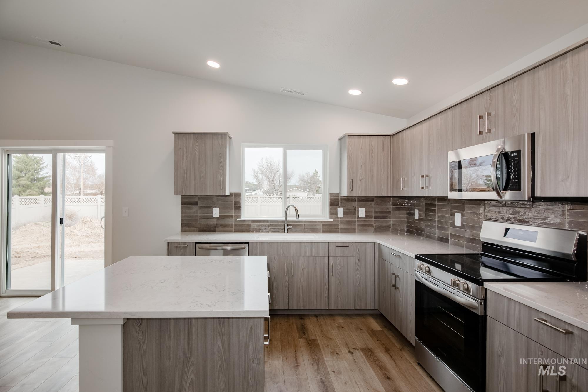 Modern kitchen featuring light wood-finish cabinetry, stainless steel appliances, and sleek countertops