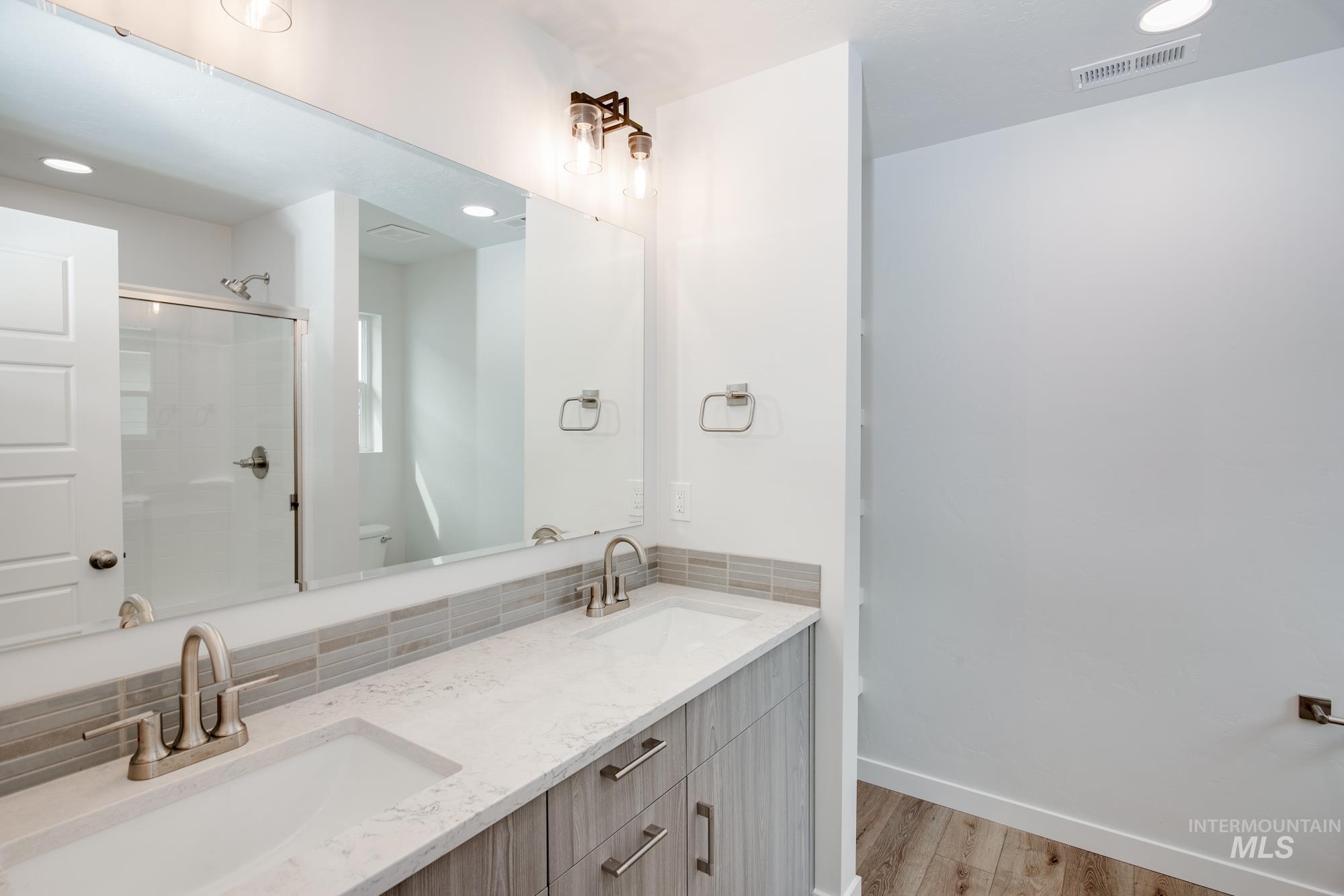 Bathroom featuring a dual vanity with undermount sinks, light wood-finish cabinetry, and brushed nickel hardware