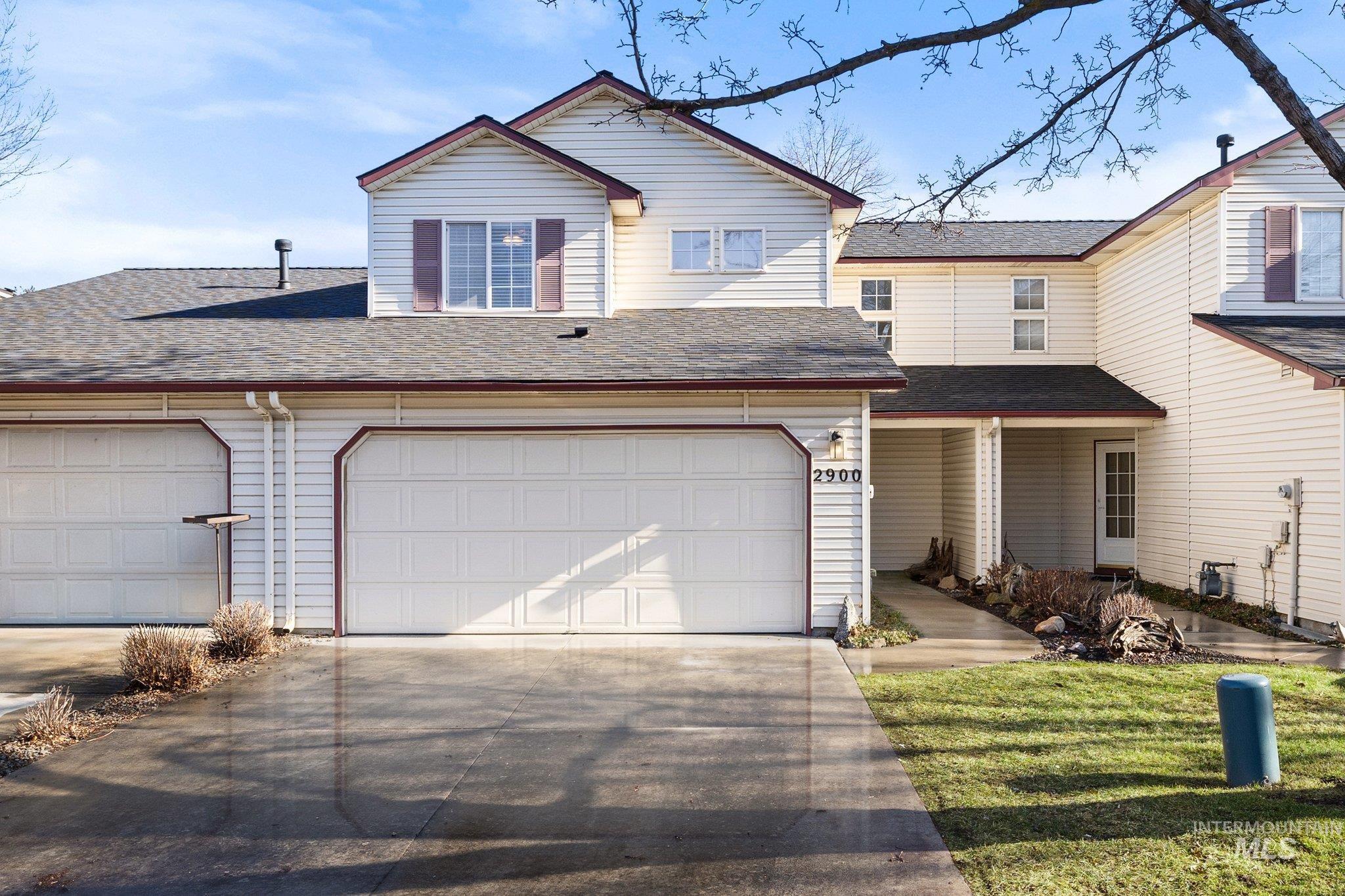 Traditional-style home featuring a shingled roof, driveway, and a garage