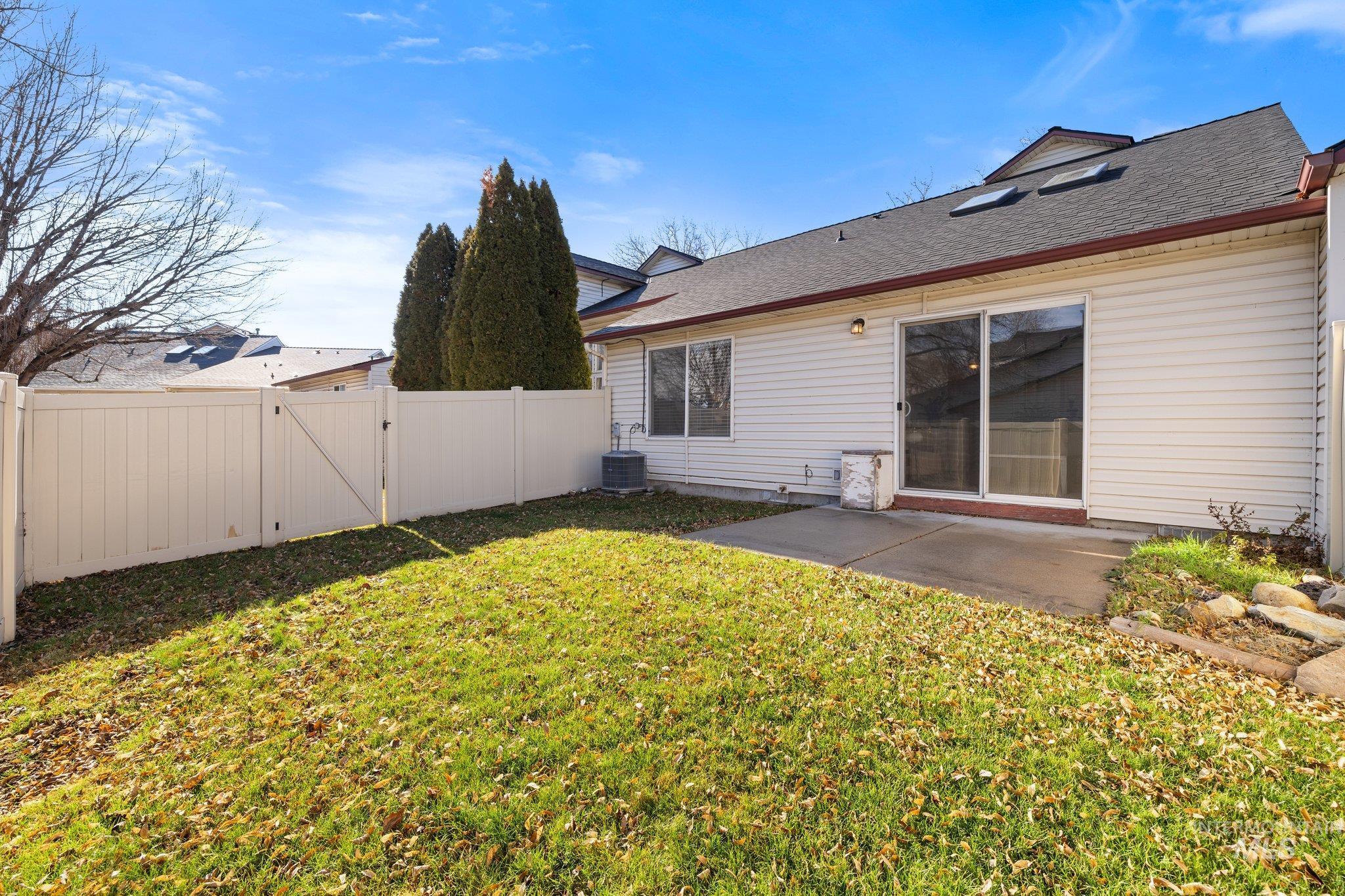 Rear view of house featuring a patio, a gate, a fenced backyard, and a shingled roof