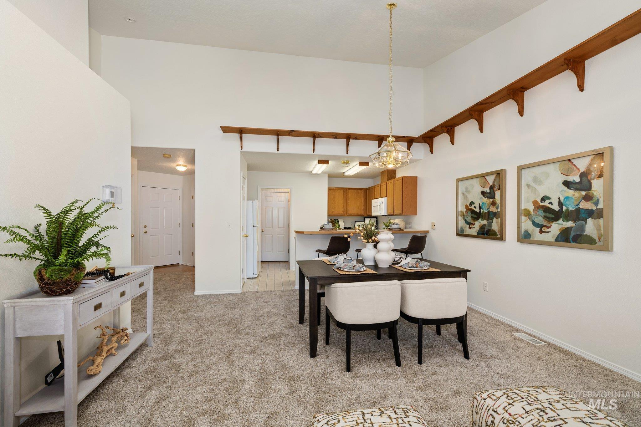 Dining space featuring light carpet and a towering ceiling