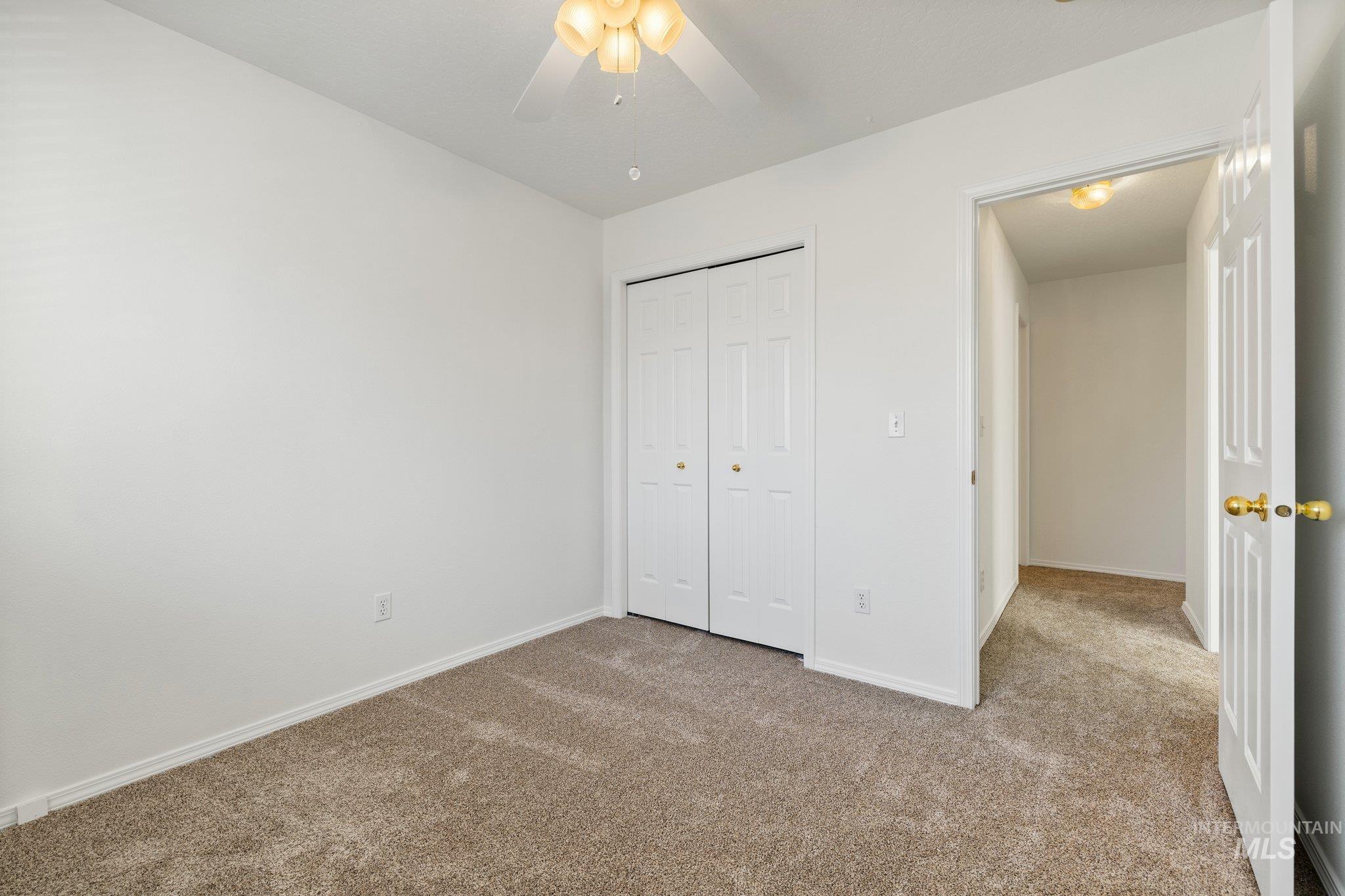 Unfurnished bedroom featuring carpet flooring, a closet, and a ceiling fan