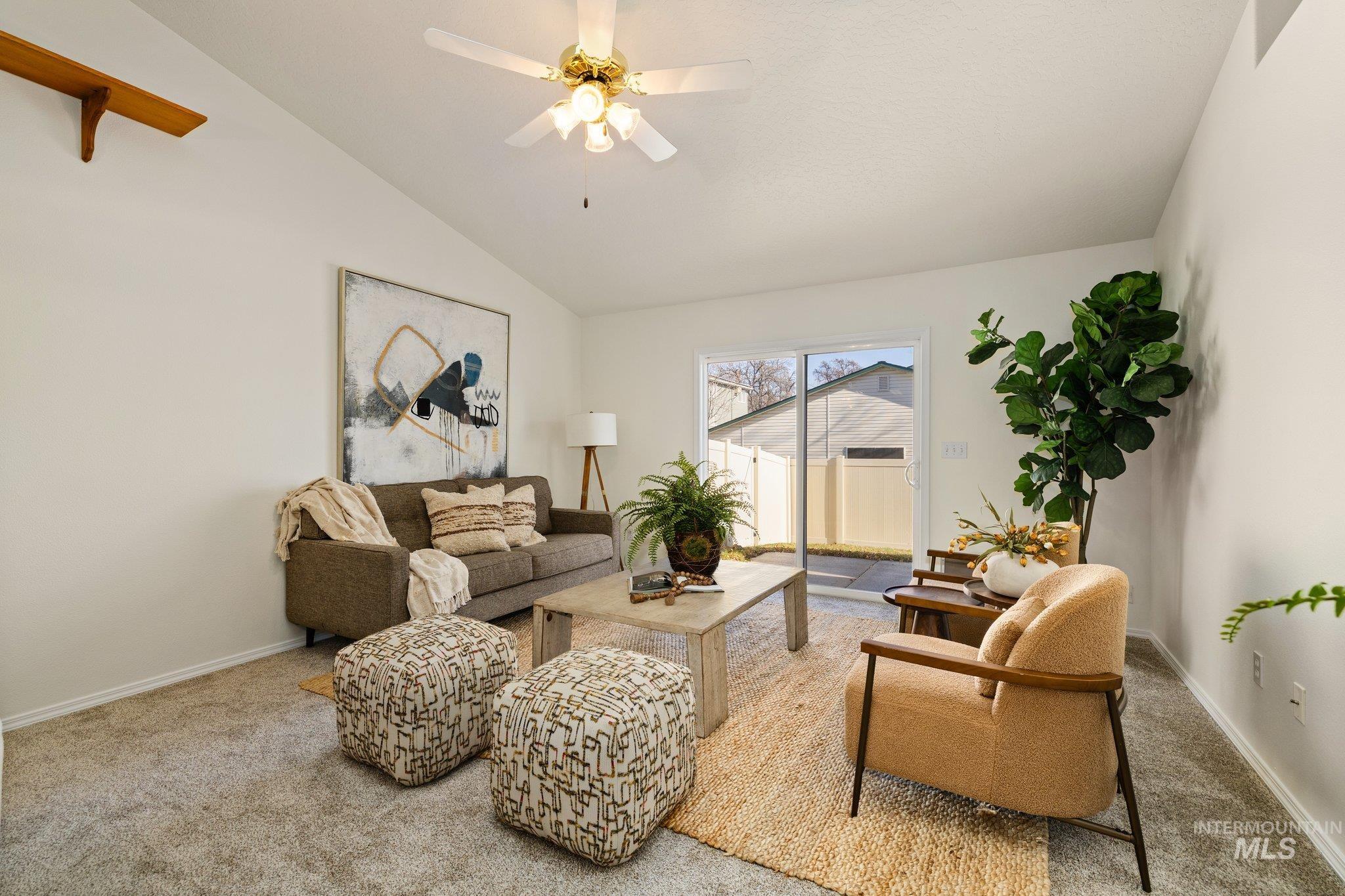 Carpeted living room with lofted ceiling and ceiling fan