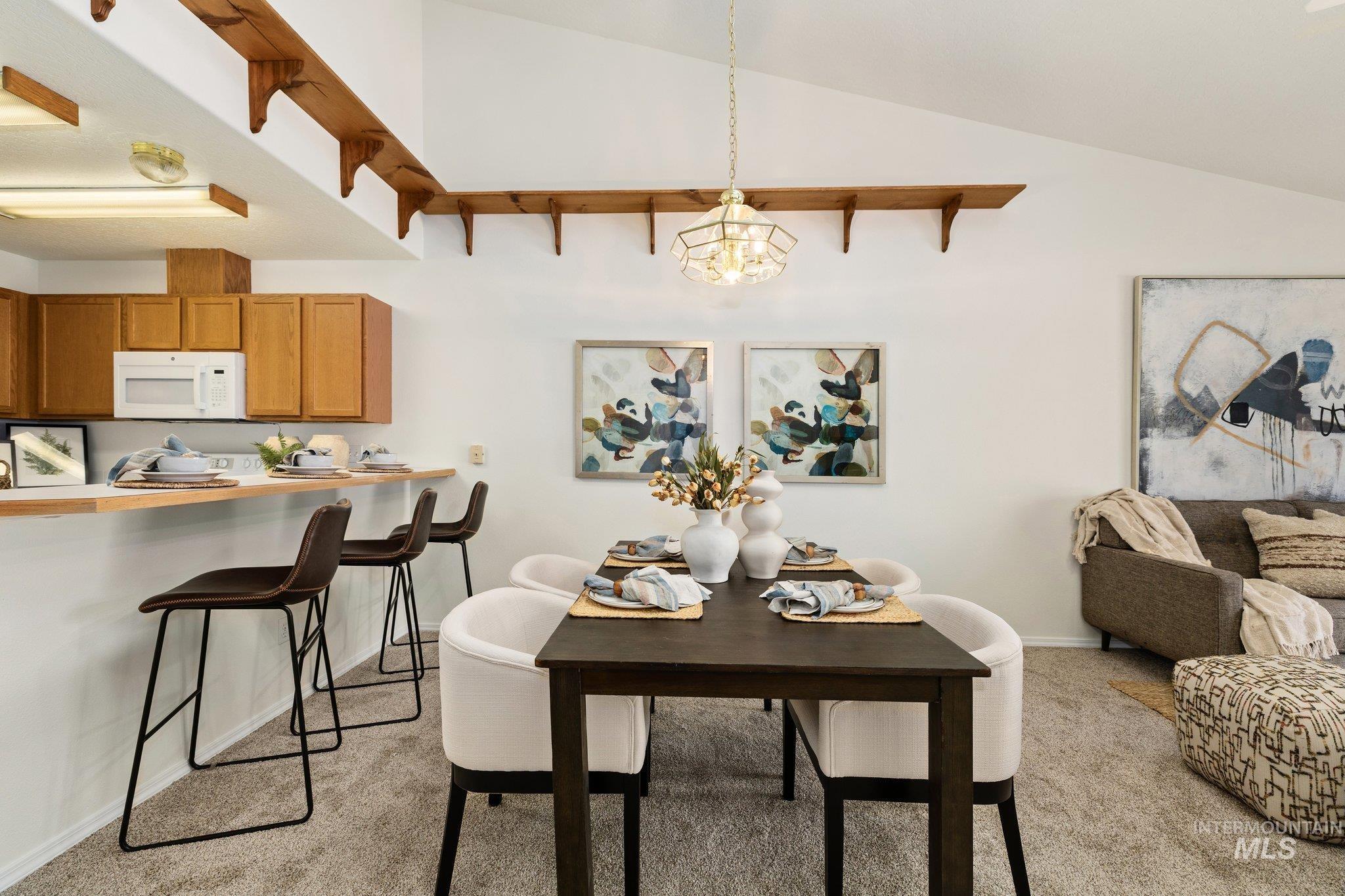 Dining space featuring light colored carpet, lofted ceiling, and a chandelier