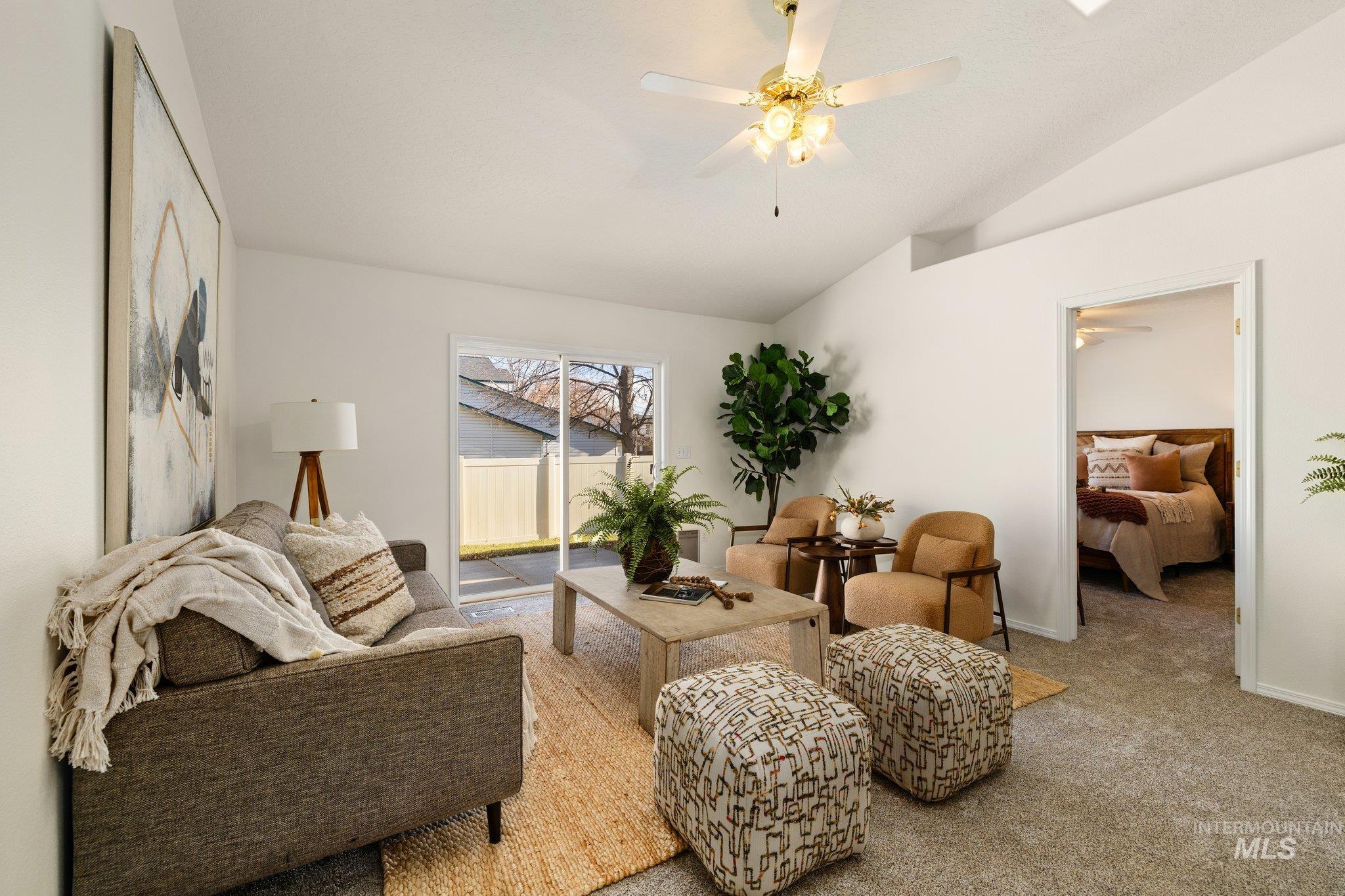 Living area with vaulted ceiling, a ceiling fan, and carpet floors
