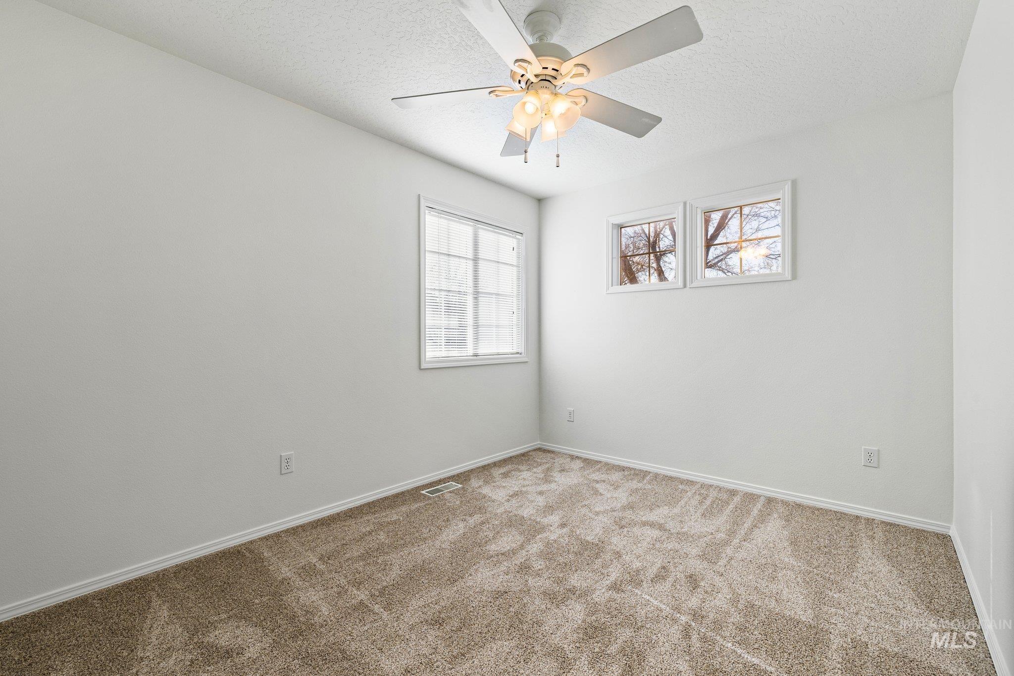 Spare room featuring carpet floors, a textured ceiling, and ceiling fan