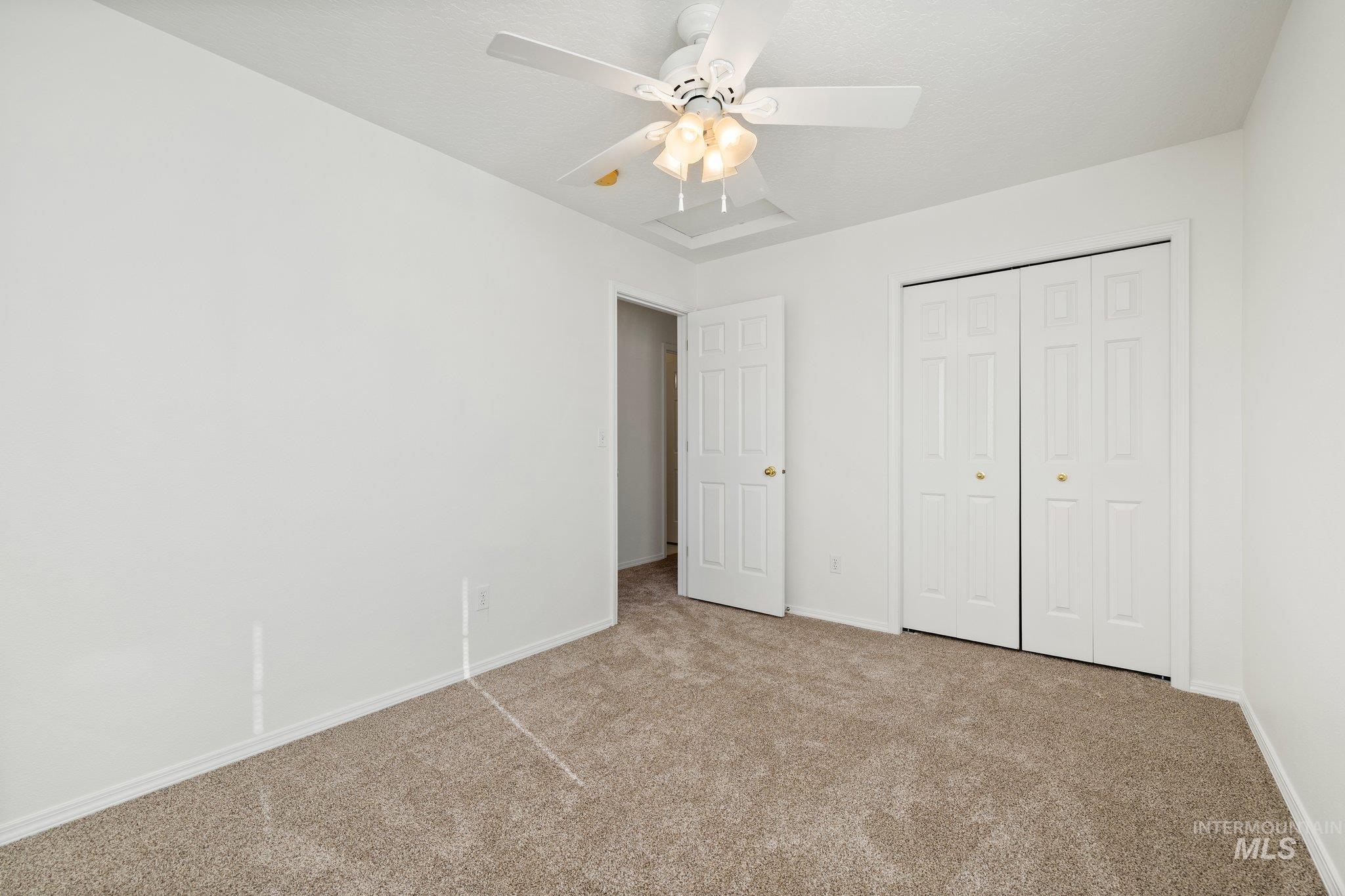 Unfurnished bedroom featuring carpet floors, a closet, and a ceiling fan