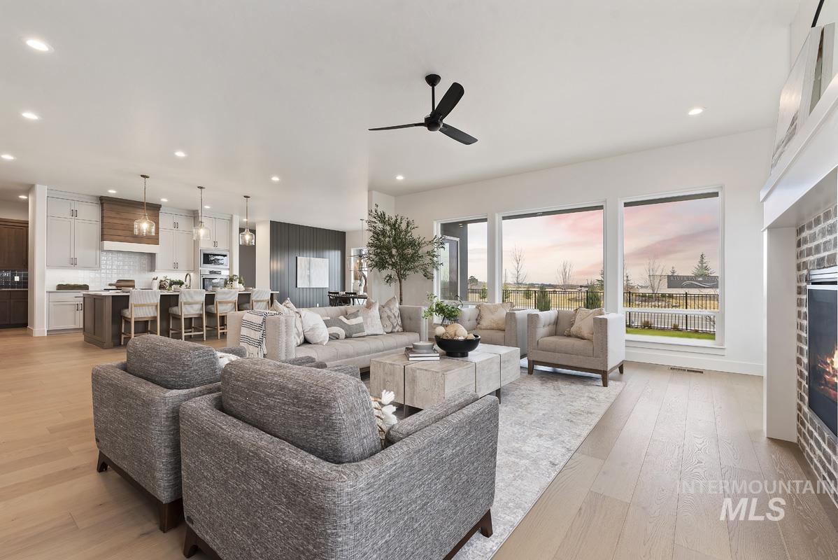 Living area with a glass covered fireplace, light wood-type flooring, recessed lighting, and ceiling fan