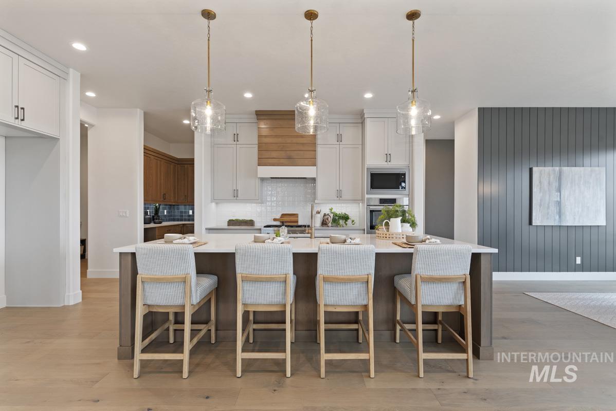 Kitchen featuring backsplash, a large island, hanging light fixtures, a breakfast bar area, and recessed lighting