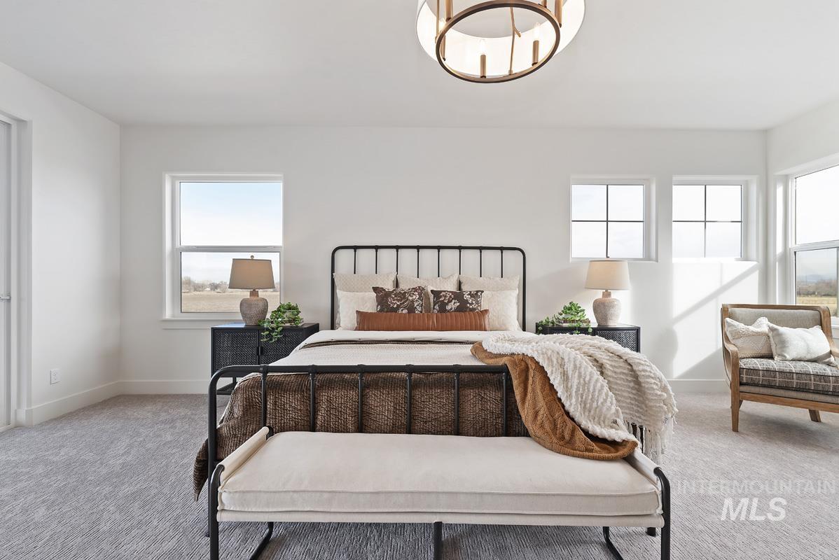 Bedroom with carpet floors, multiple windows, and a chandelier