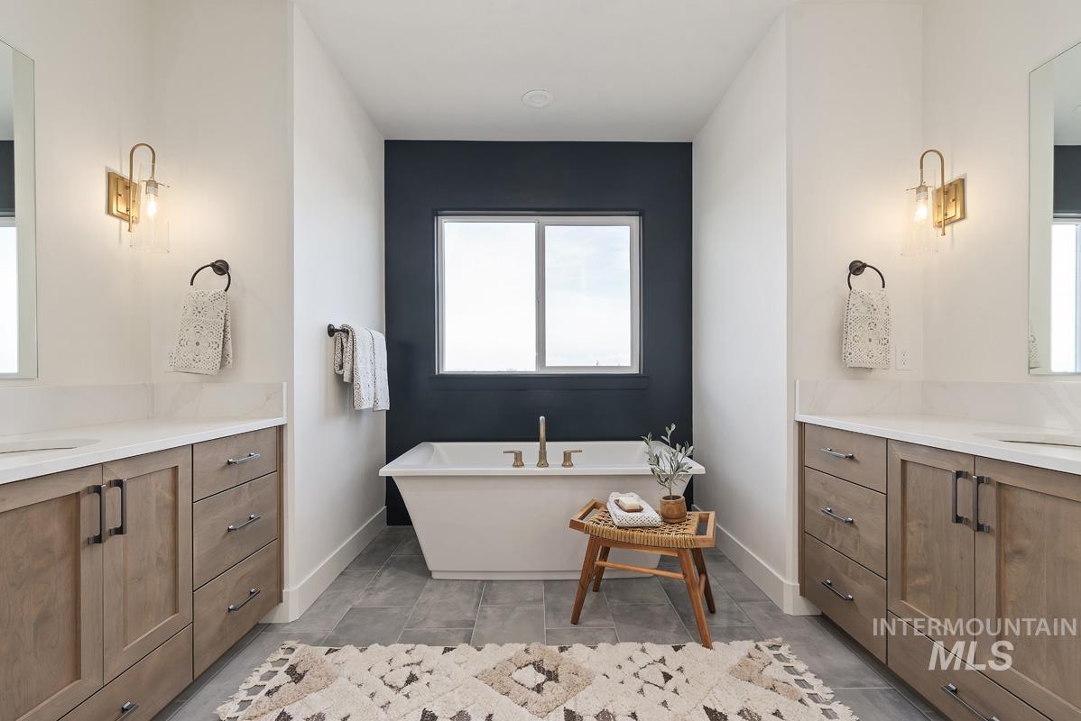Bathroom with two vanities, a freestanding bath, and light tile patterned floors