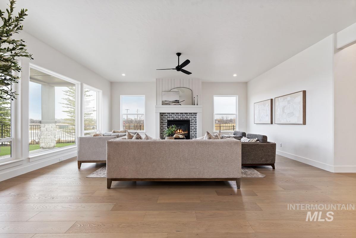 Living area with light wood-style flooring, a tiled fireplace, ceiling fan, and recessed lighting