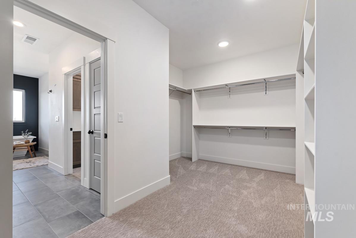 Walk in closet with light carpet and light tile patterned floors