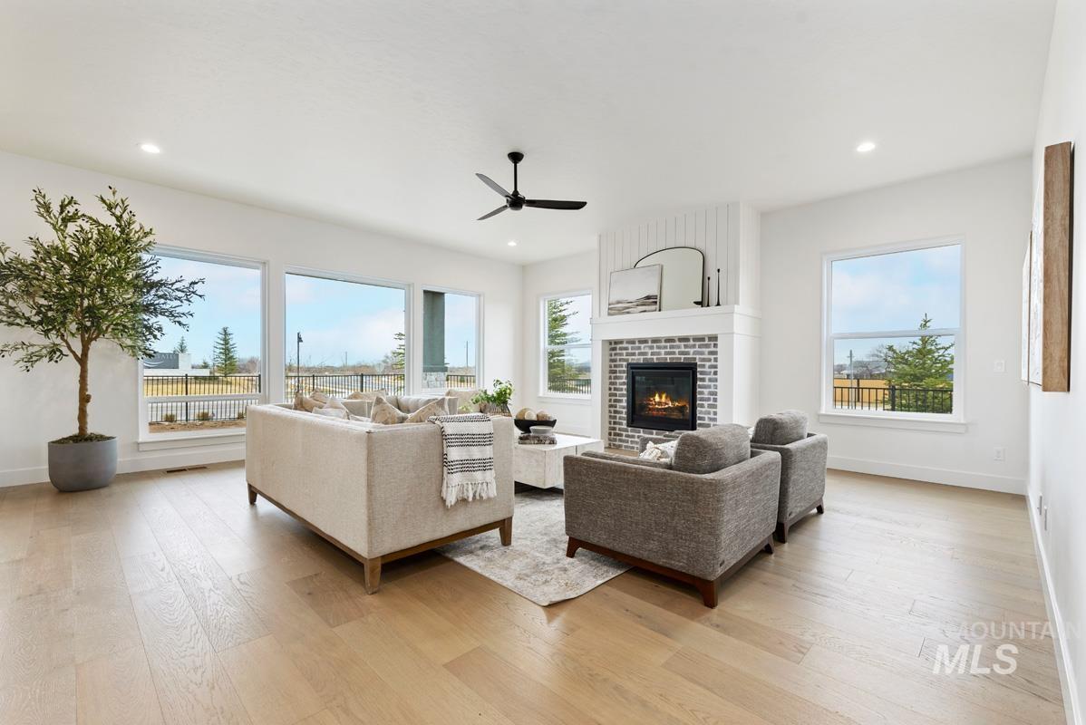 Living area with a fireplace, light wood-style floors, a ceiling fan, and recessed lighting