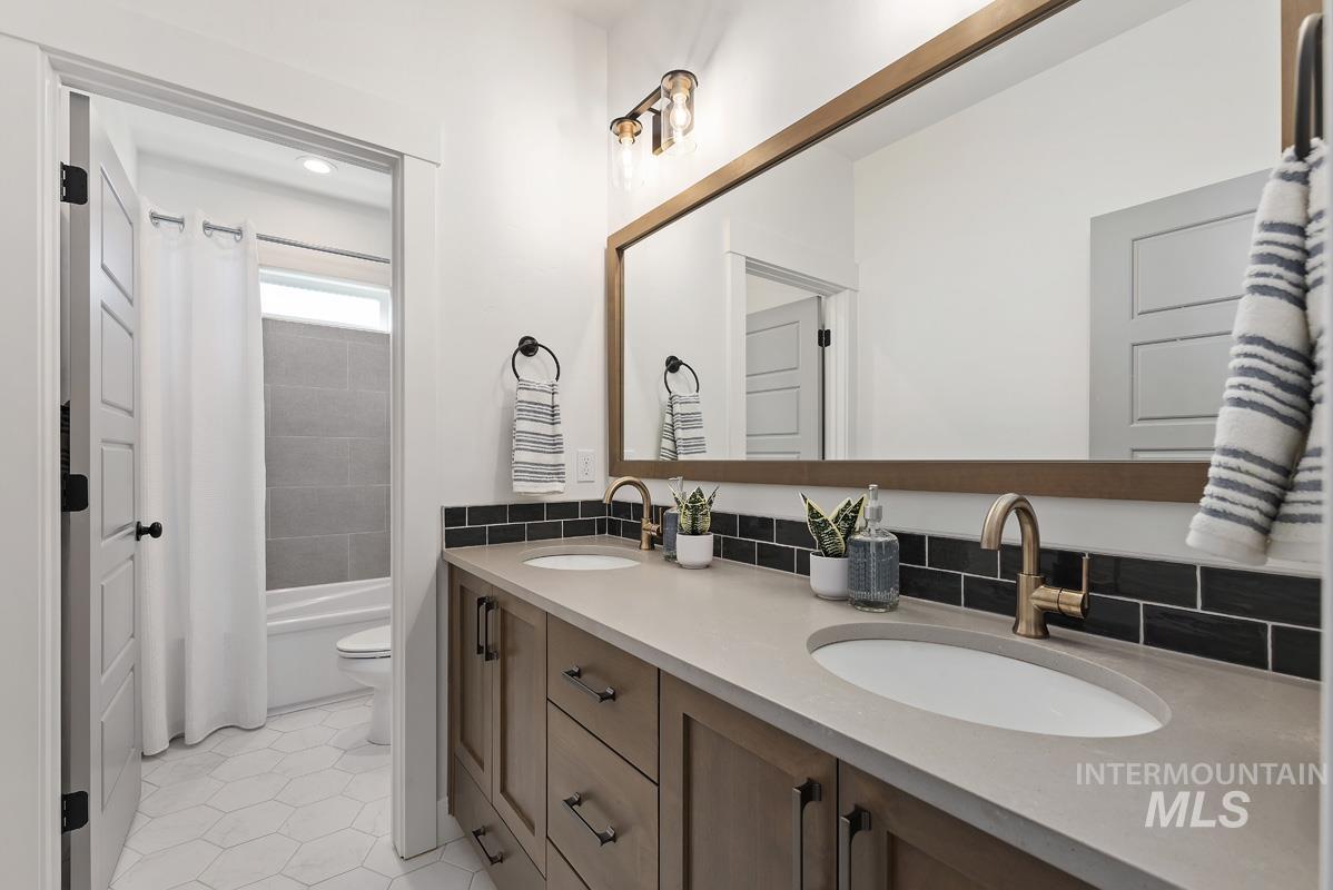 Bathroom featuring double vanity, light tile patterned floors, and shower / bathtub combination with curtain