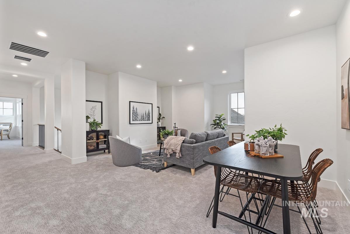 Dining room with light colored carpet and recessed lighting