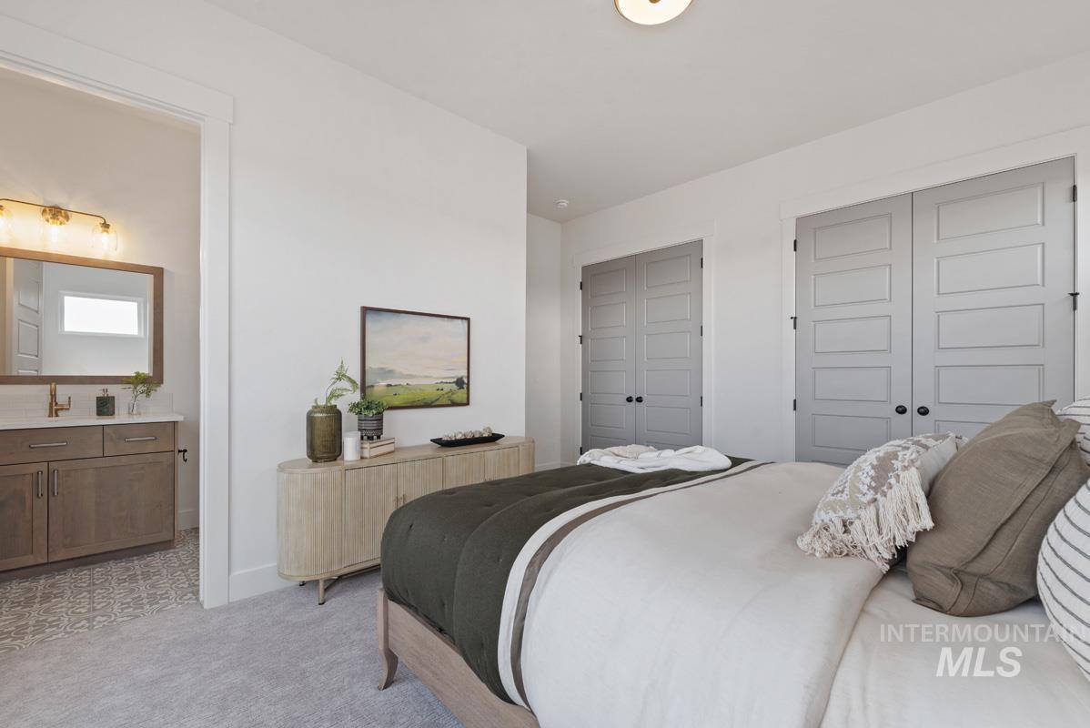 Bedroom featuring two closets, light colored carpet, and ensuite bathroom