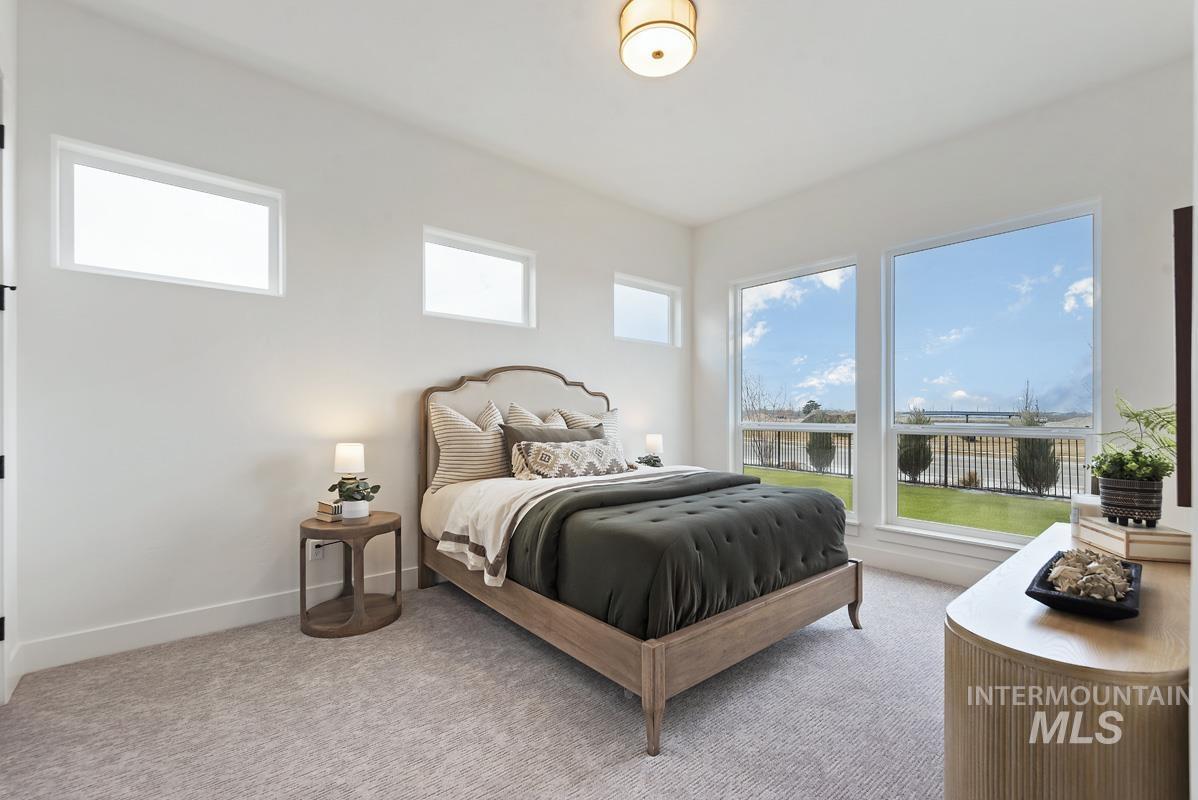 Bedroom with multiple windows, light carpet, and a water view