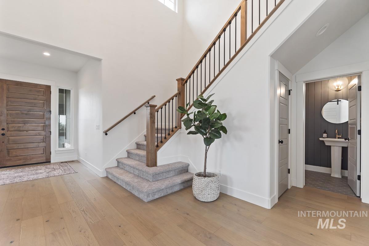 Foyer entrance featuring light wood finished floors, a high ceiling, recessed lighting, and stairs