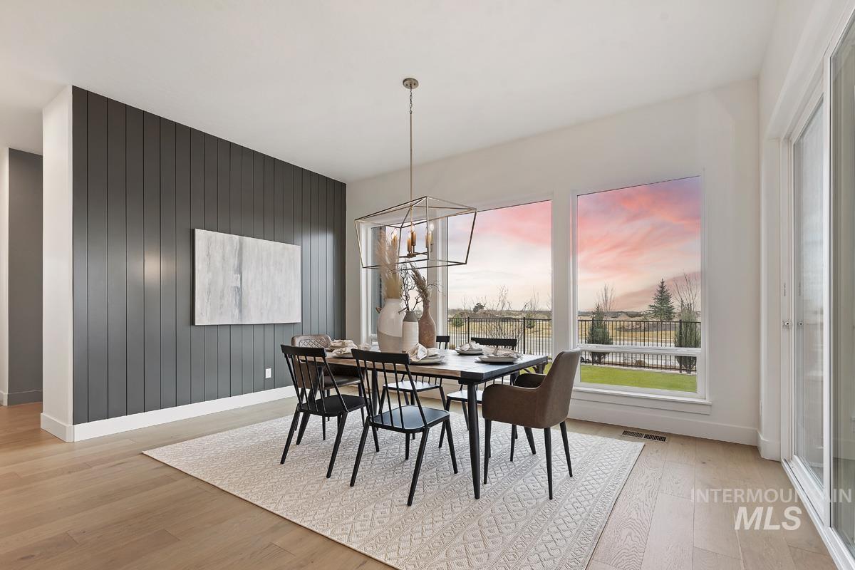 Dining room featuring a chandelier, light wood-type flooring, and wooden walls