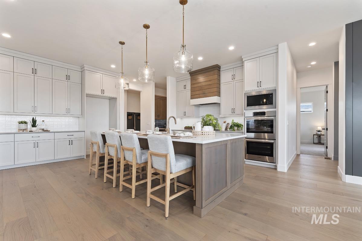 Kitchen featuring tasteful backsplash, a kitchen breakfast bar, stainless steel appliances, light wood-style flooring, and recessed lighting