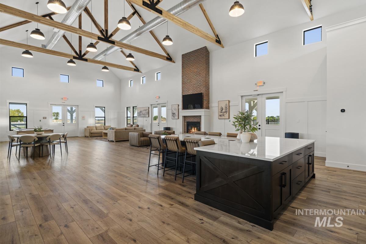 Kitchen with high vaulted ceiling, a fireplace, dark cabinets, open floor plan, and decorative light fixtures