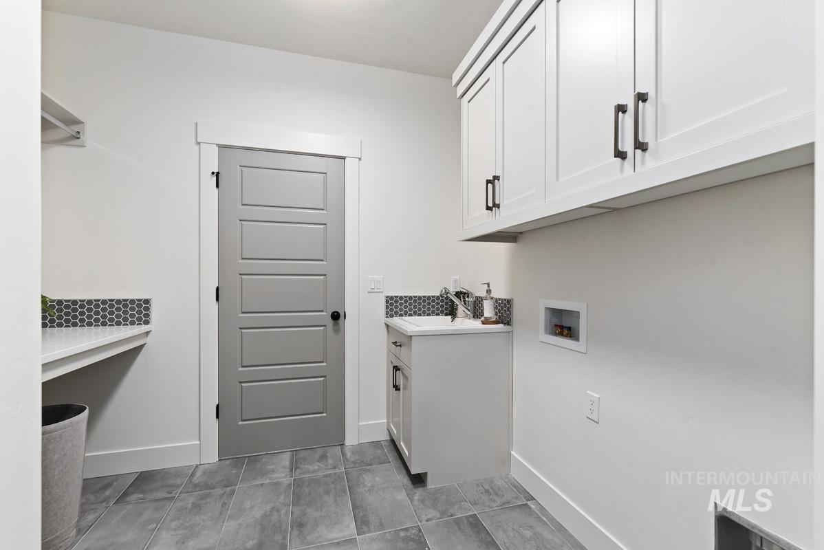 Laundry room featuring hookup for a washing machine, cabinet space, and light tile patterned floors