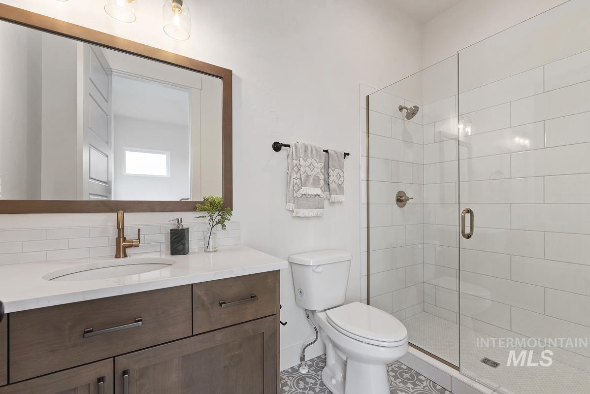Bathroom featuring a shower stall, vanity, and tile patterned flooring