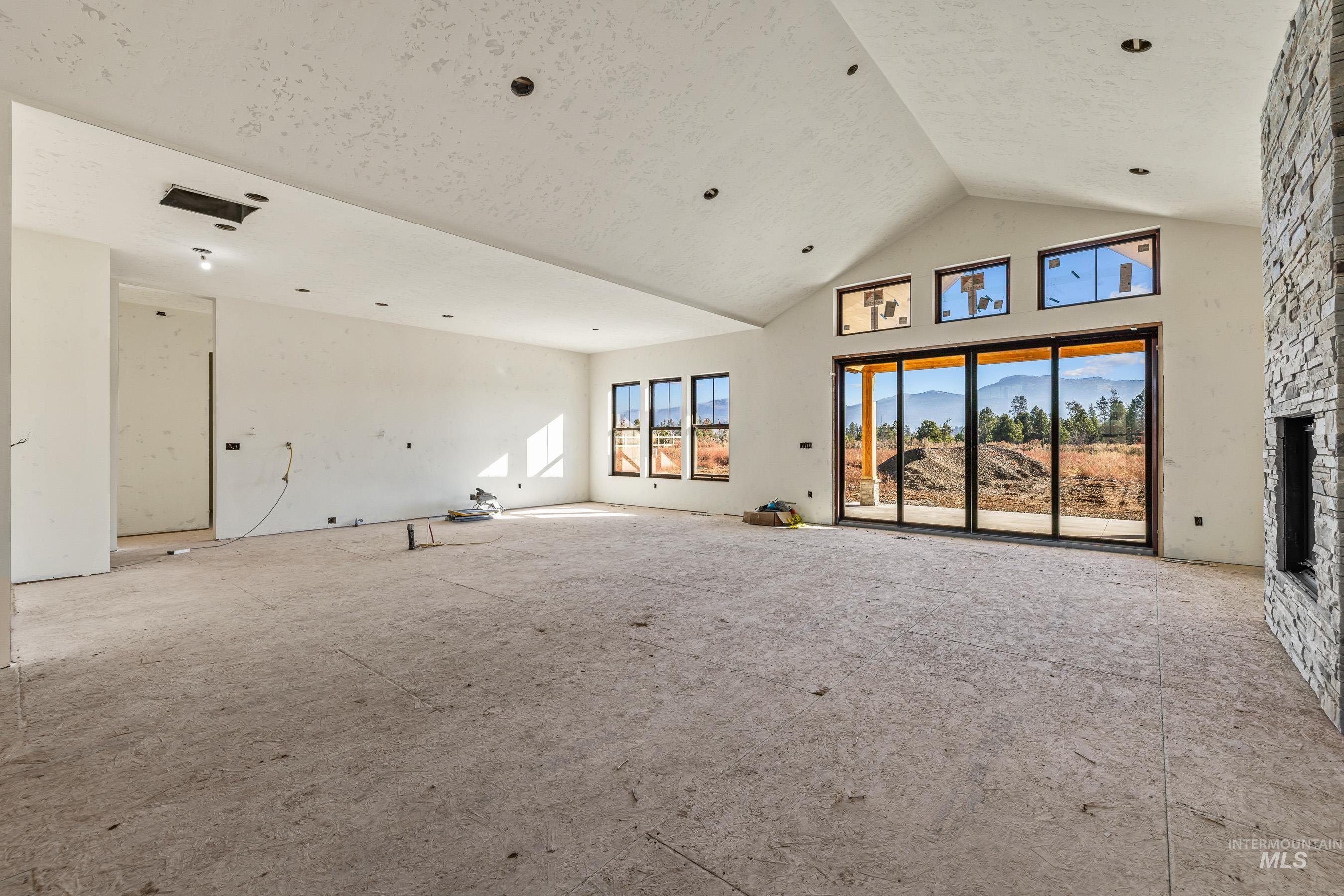 Unfurnished living room featuring high vaulted ceiling, a stone fireplace, and a mountain view