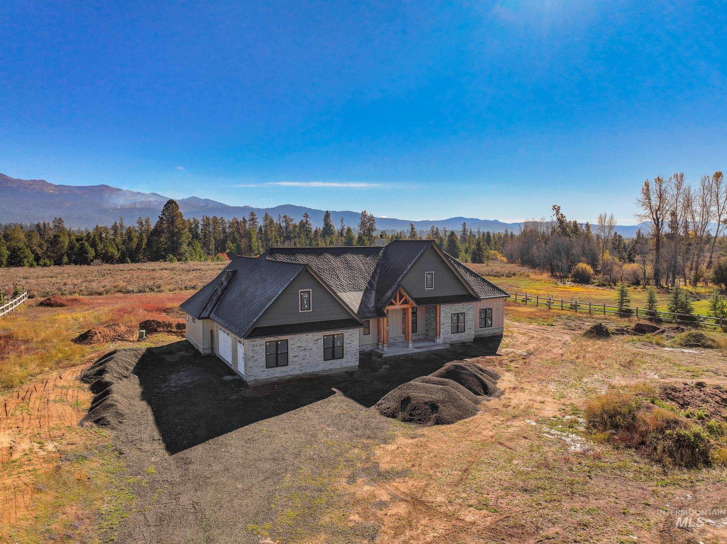 View of front facade featuring a view of rural / pastoral area, a garage, a mountain view, and dirt driveway
