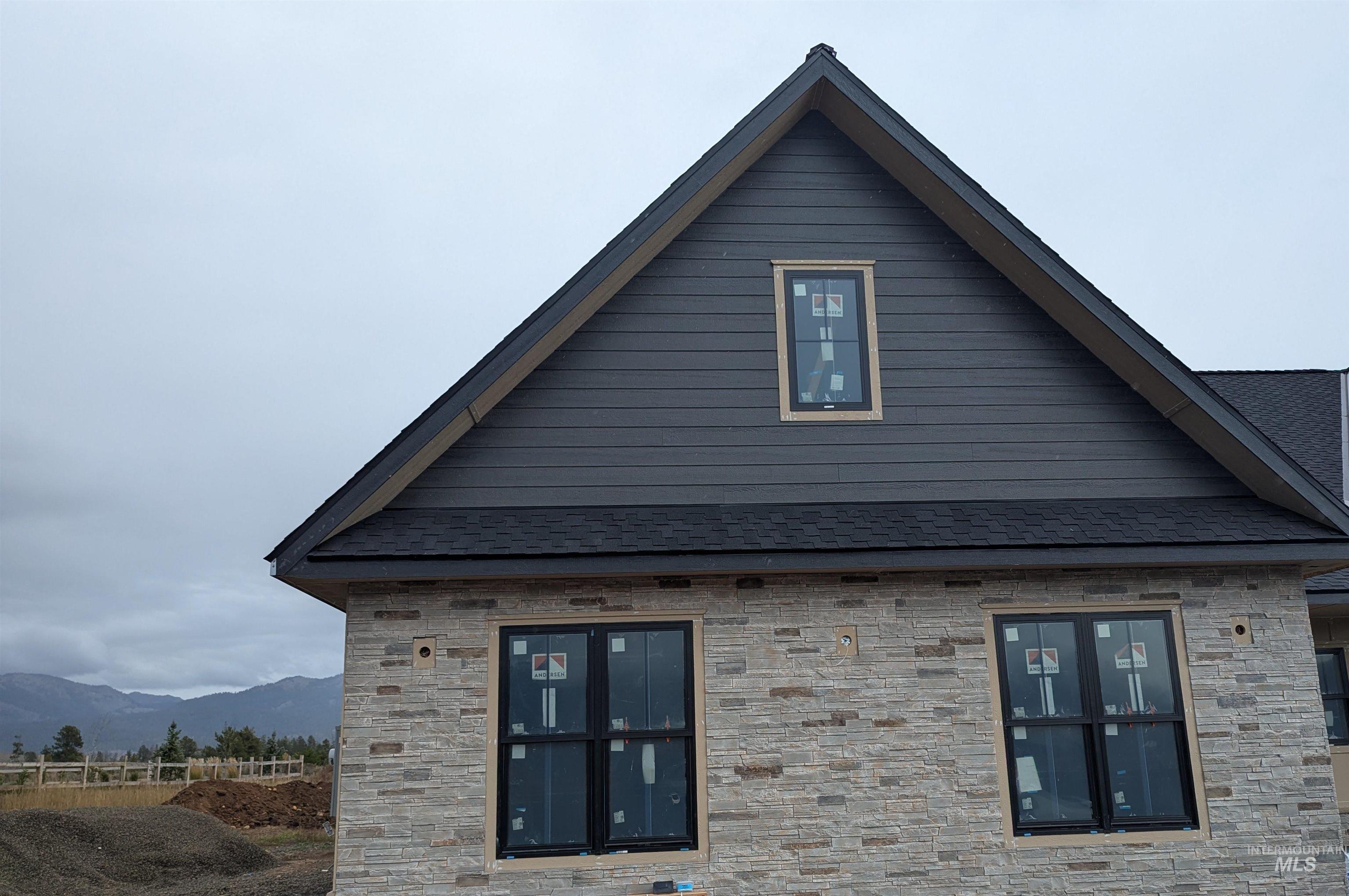 View of side of home featuring stone siding and a shingled roof