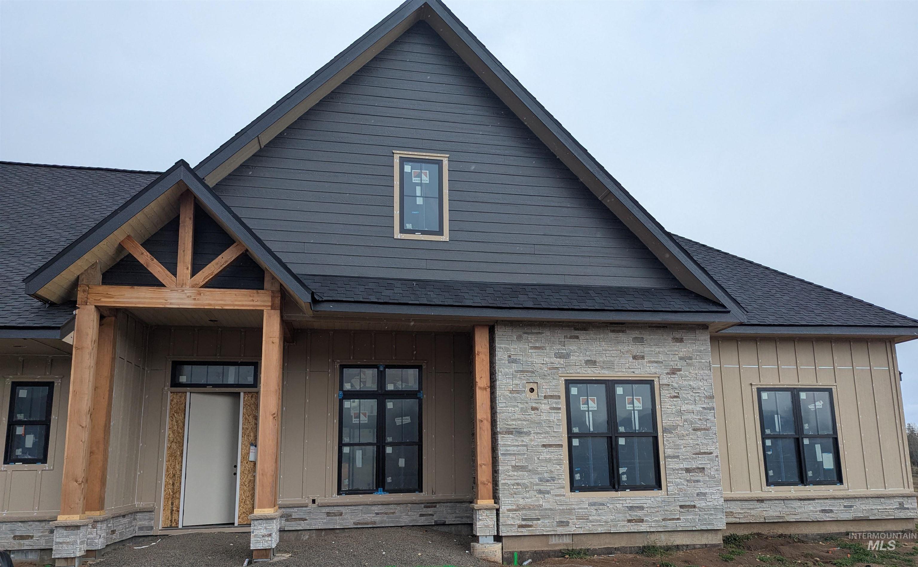 View of front of property with a porch, roof with shingles, board and batten siding, and stone siding